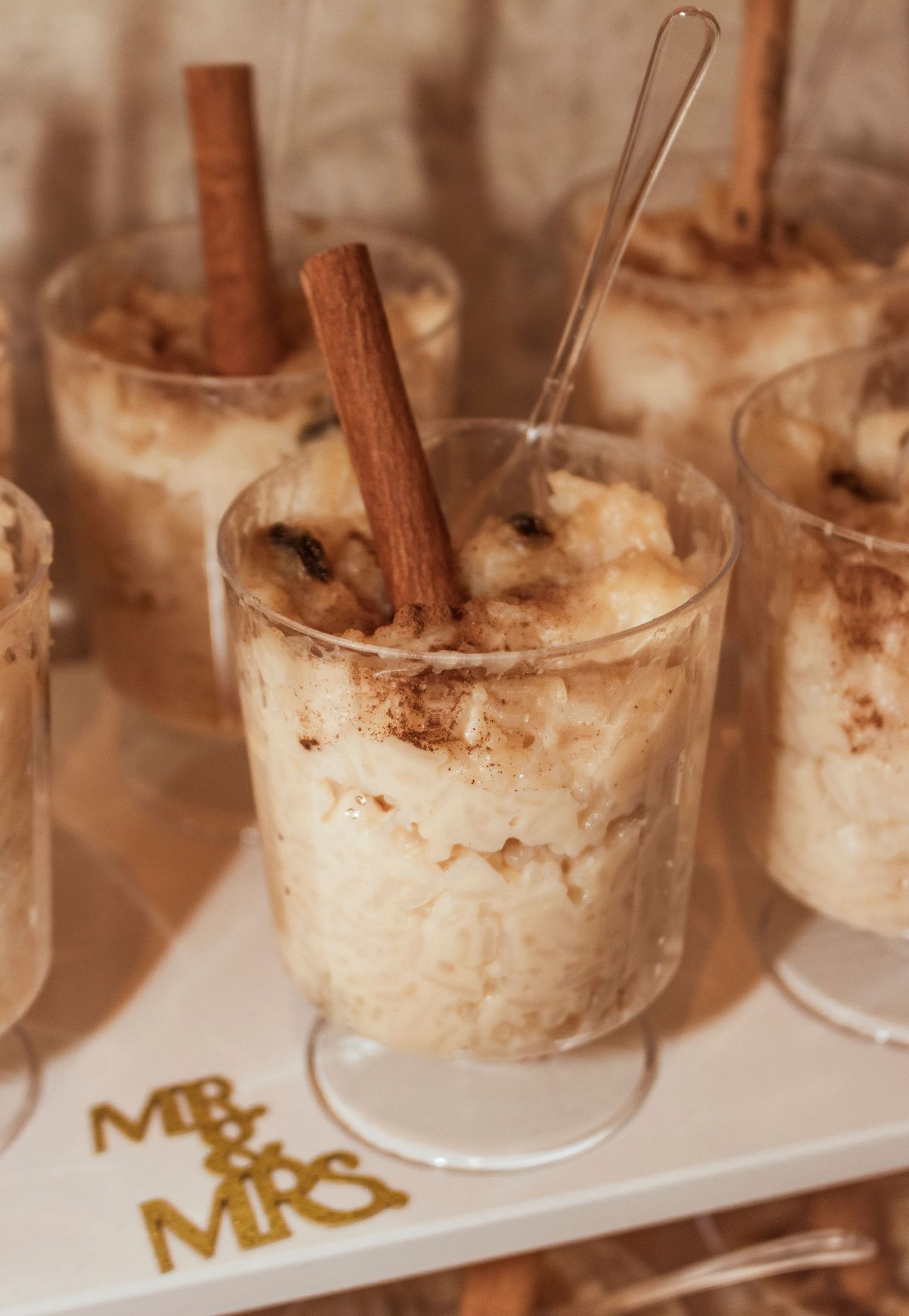 Creamy dessert shooters garnished with cinnamon sticks and 'Mr & Mrs' text on serving tray.