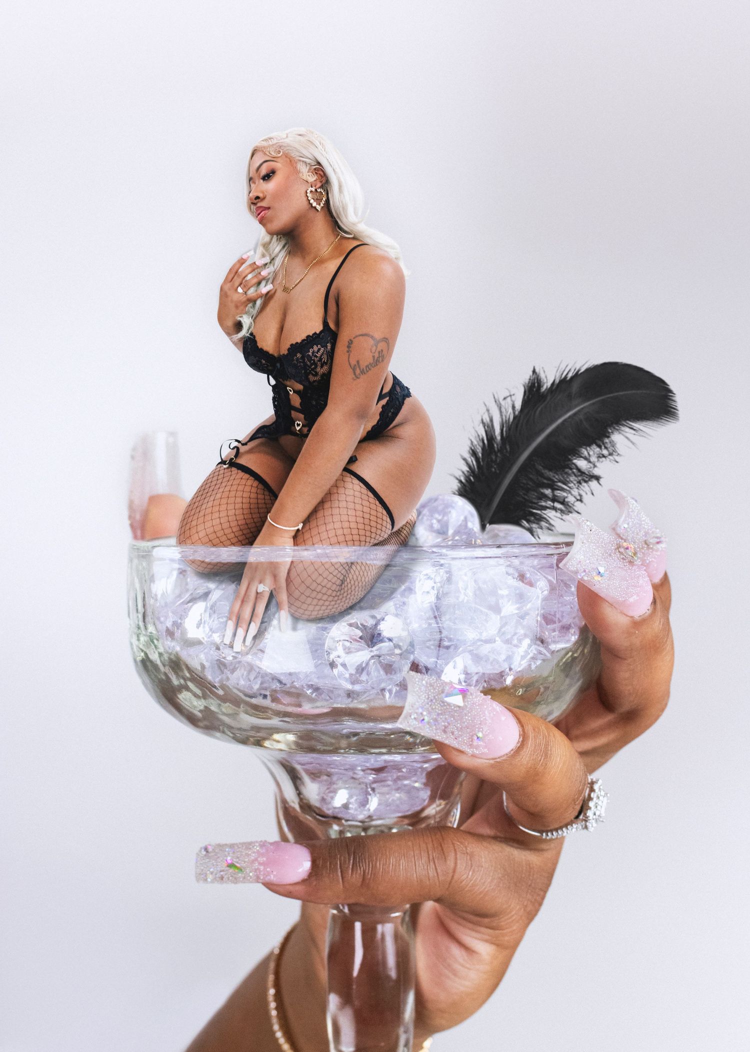 Artistic photo of a model in black lingerie posing in a giant martini glass with silver decor.