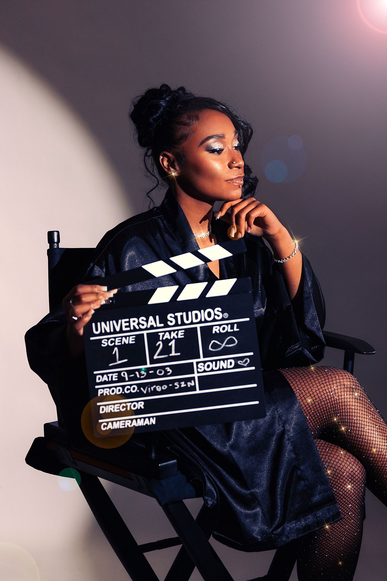 Glamorous portrait of someone holding movie clapperboard while sitting in director's chair.