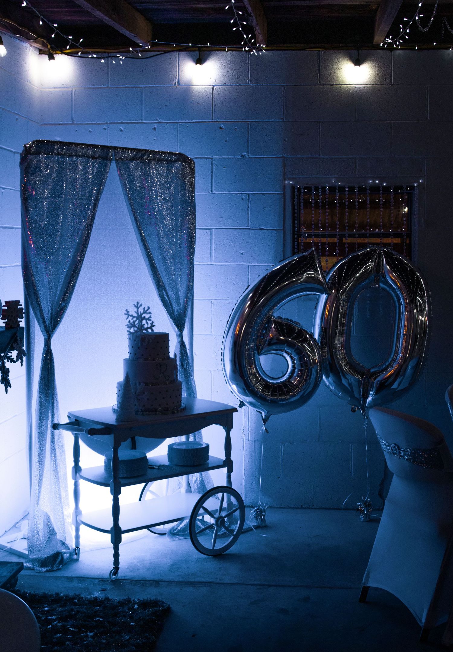 Dark and moody photos of an elegant seating area with velvet chairs and drapes illuminated in ethereal blue lighting.