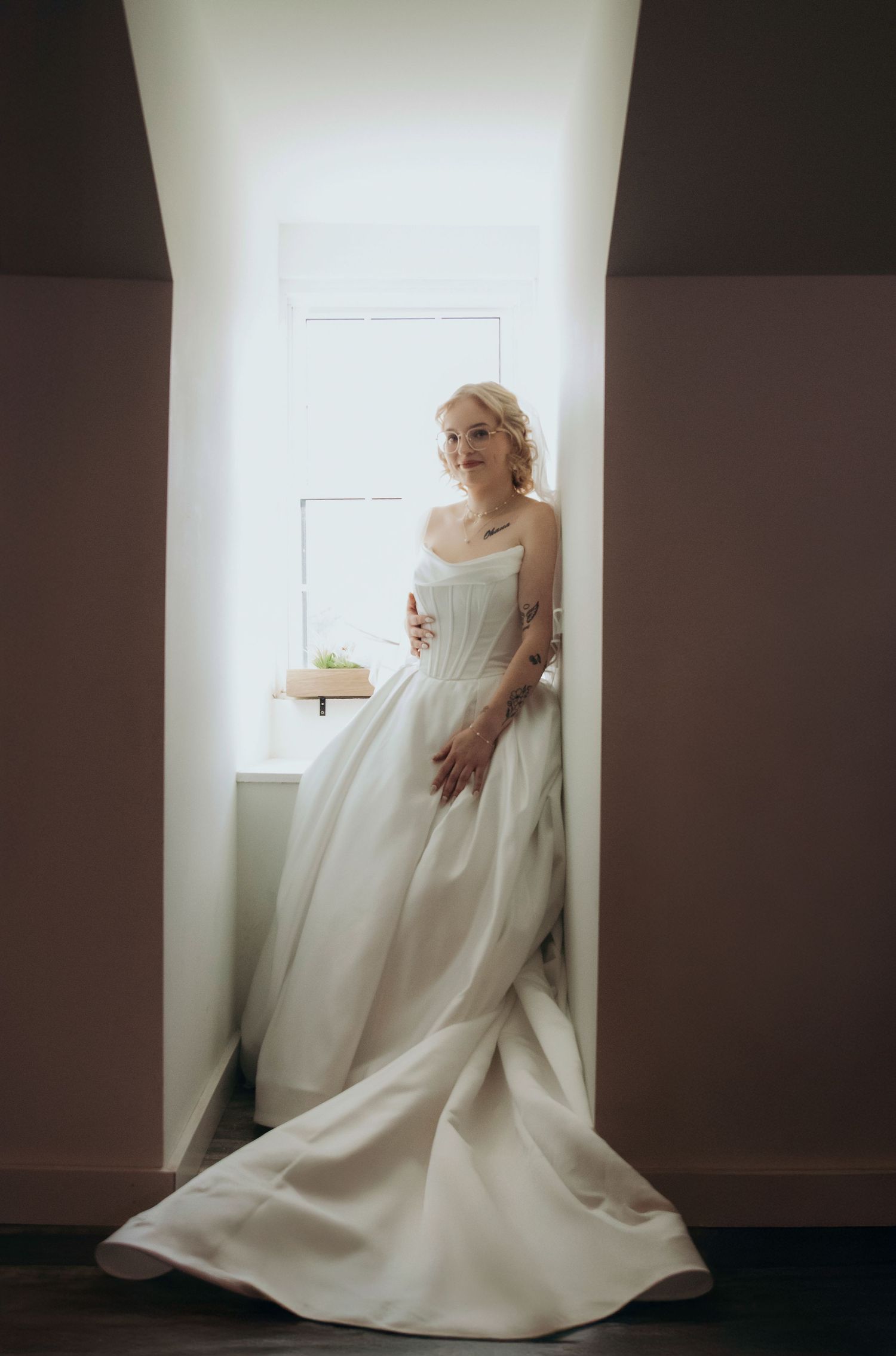 A figure in a flowing white dress creates dramatic poses against a minimalist white wall and dark floor.