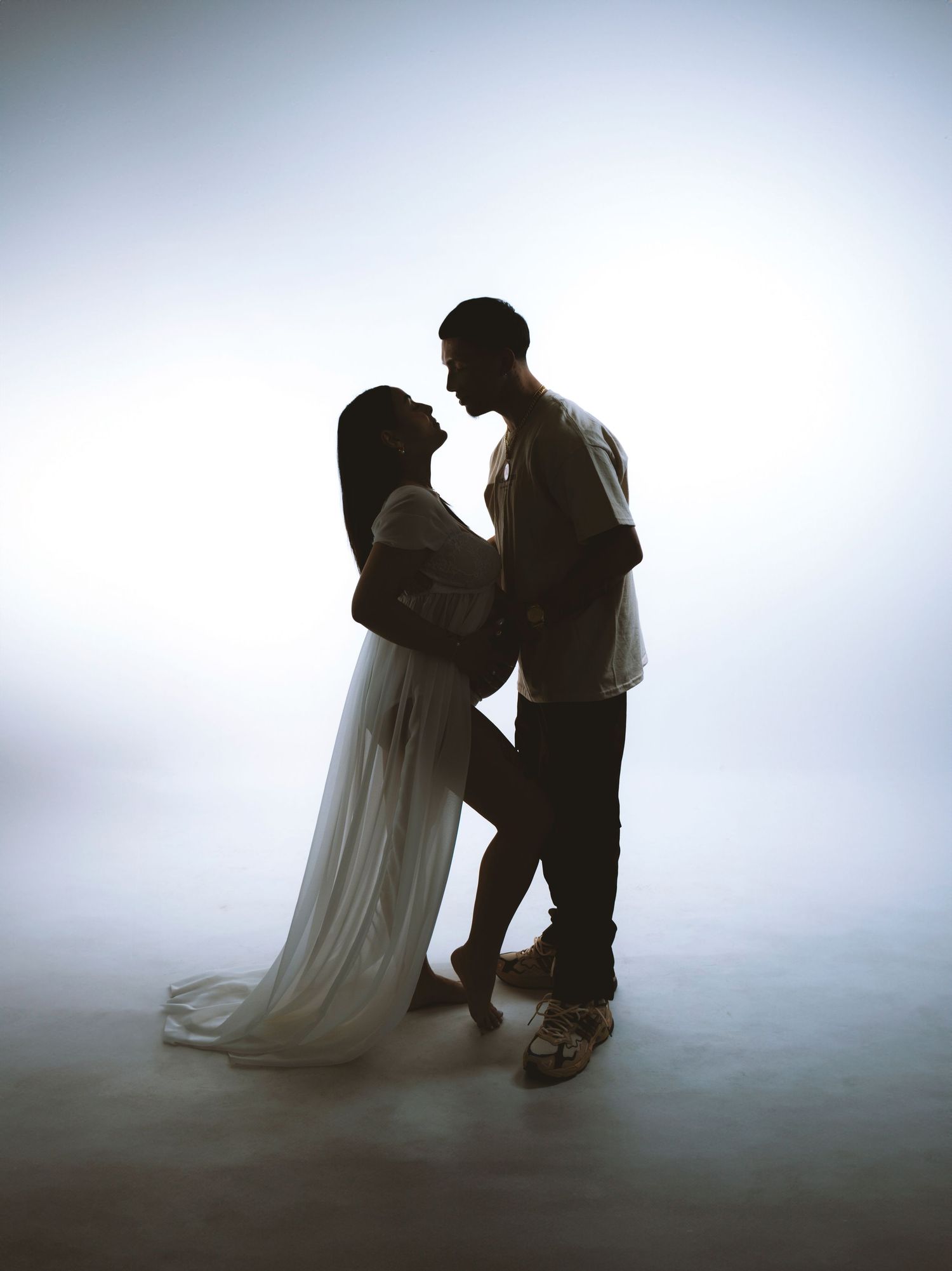 Silhouette of an intimate couple's moment against a bright backlit background.