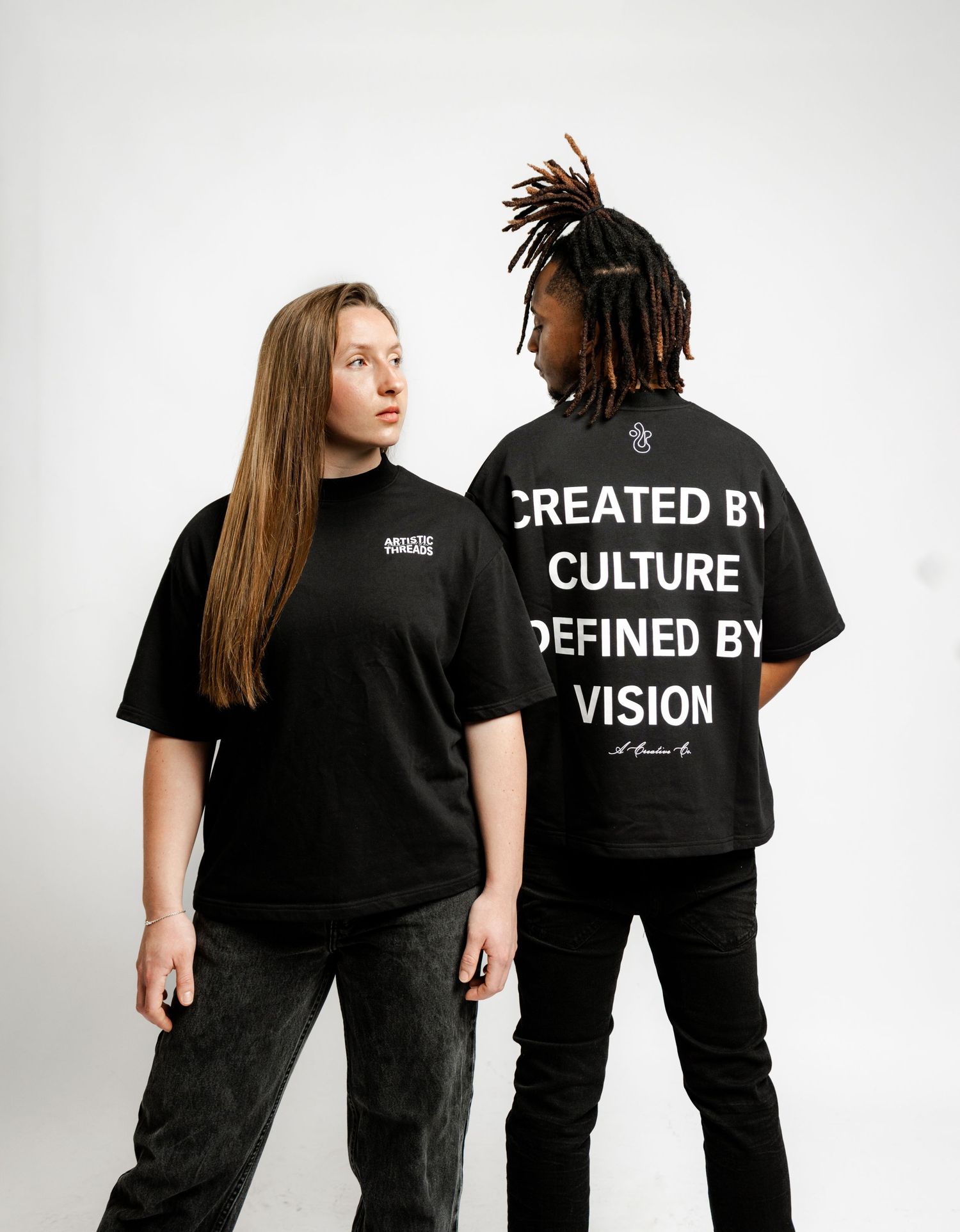 Two models wearing matching black t-shirts with statement text posing against white background.