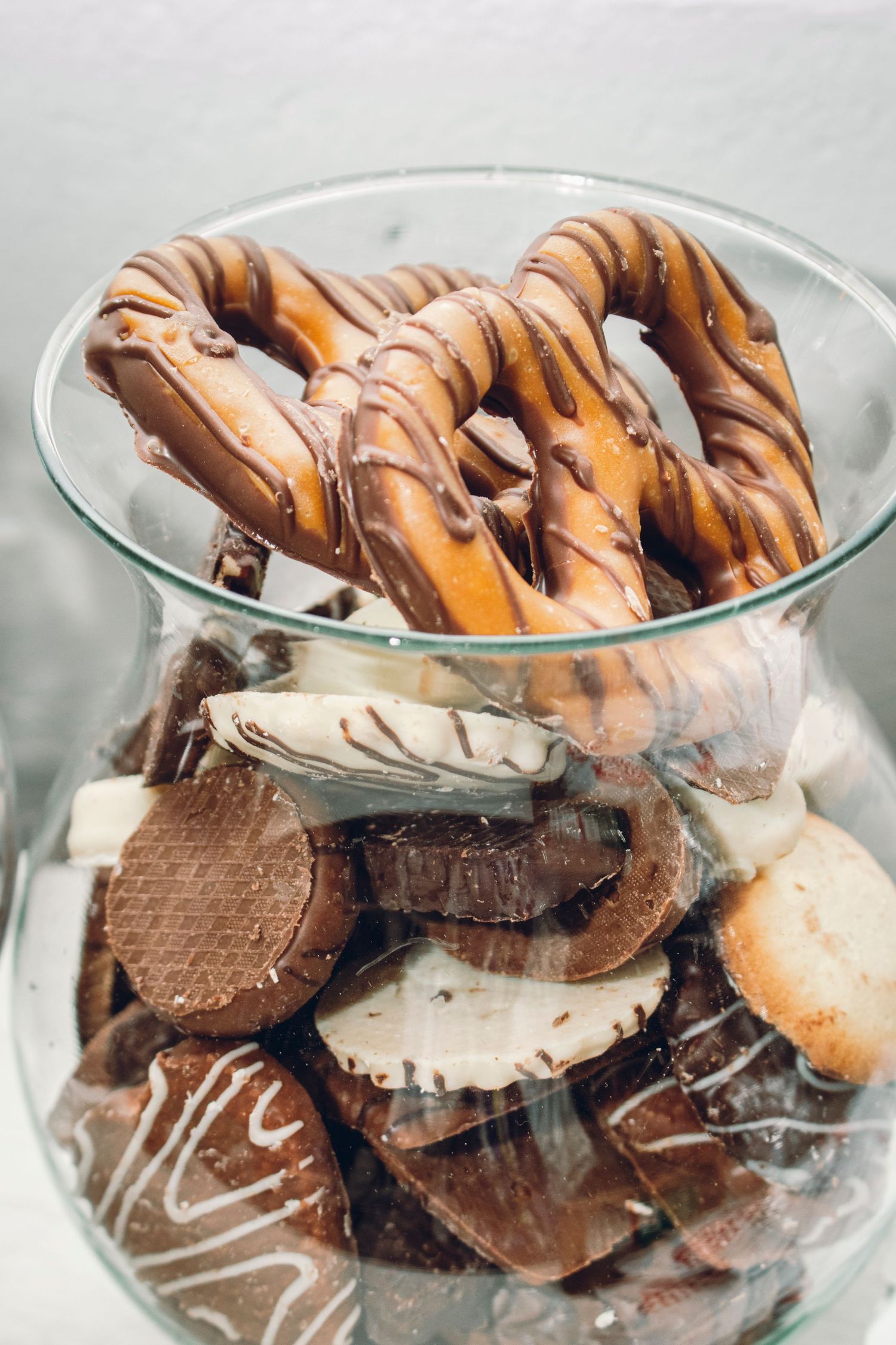 Chocolate and cookie dessert layered parfaits with drizzle in clear glass serving bowls shown from different angles.