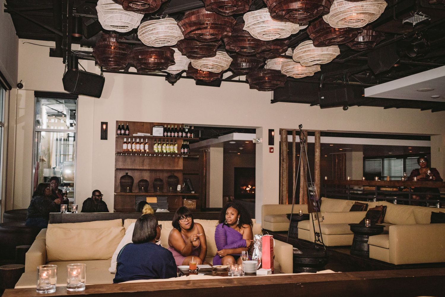 Diners enjoy their meals at white-lit tables in a cozy restaurant interior with dark ceilings and contemporary decor.