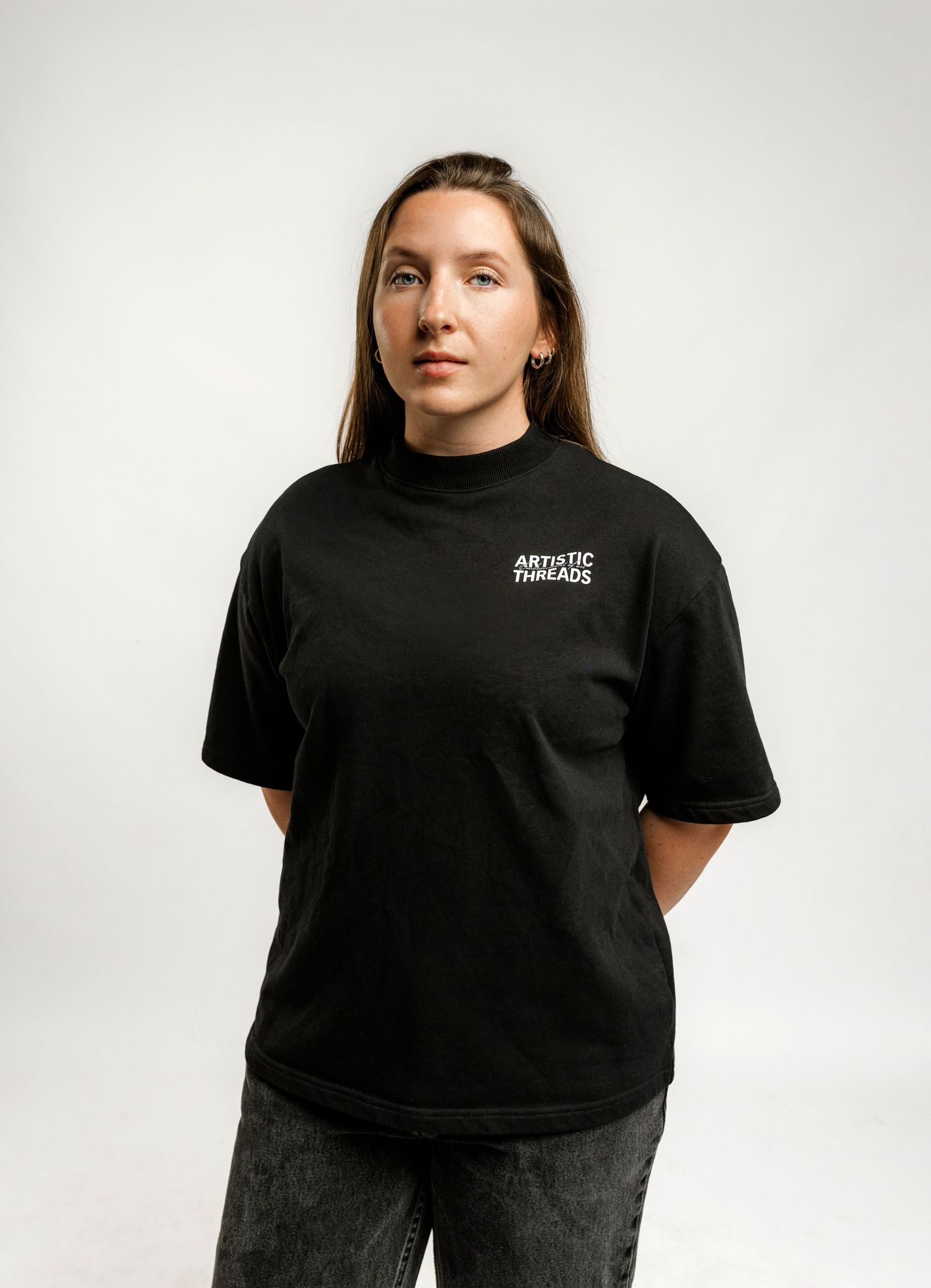 Black t-shirt with small brand logo worn against white background.