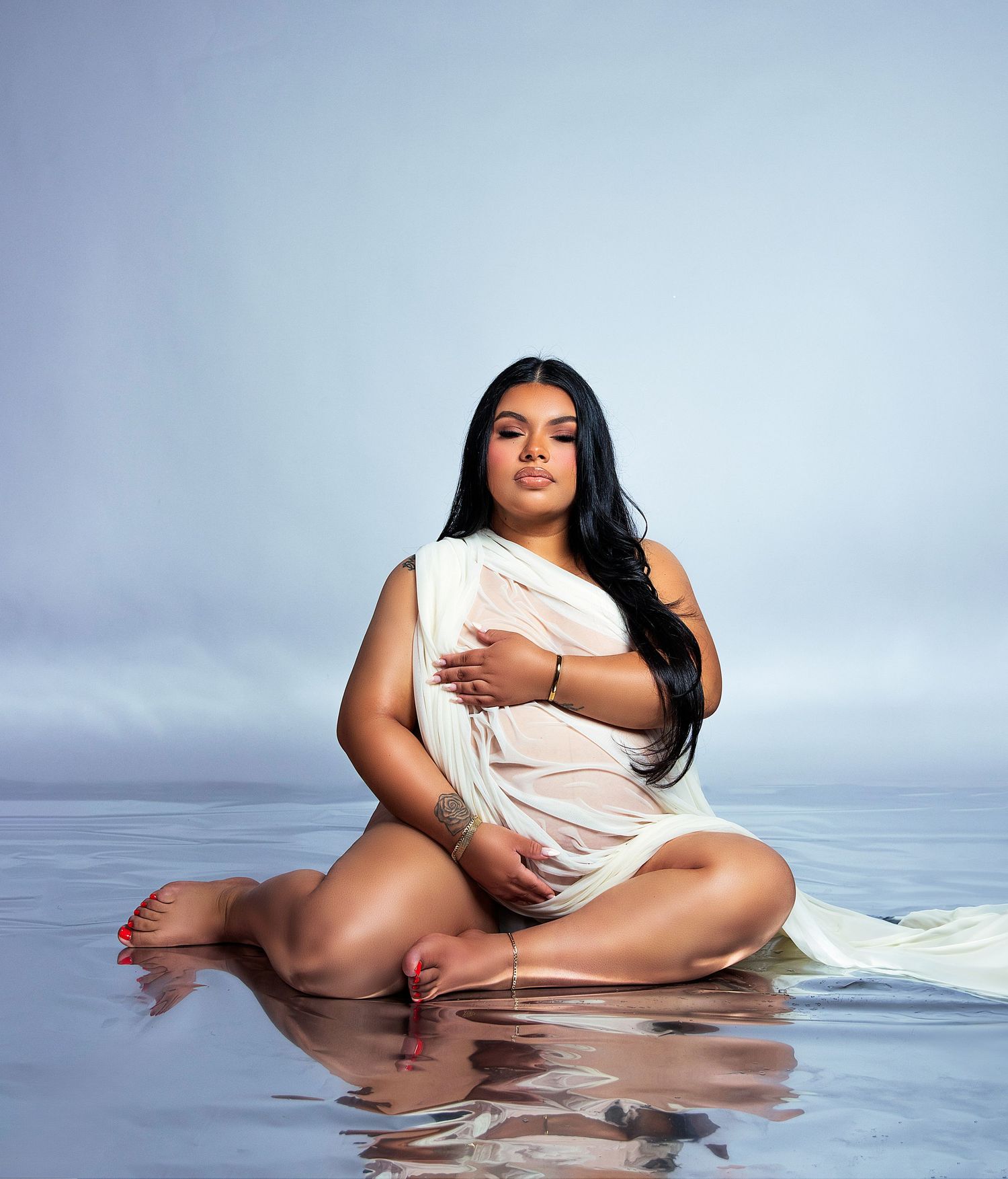 Serene maternity portrait with water elements and reflective surface.