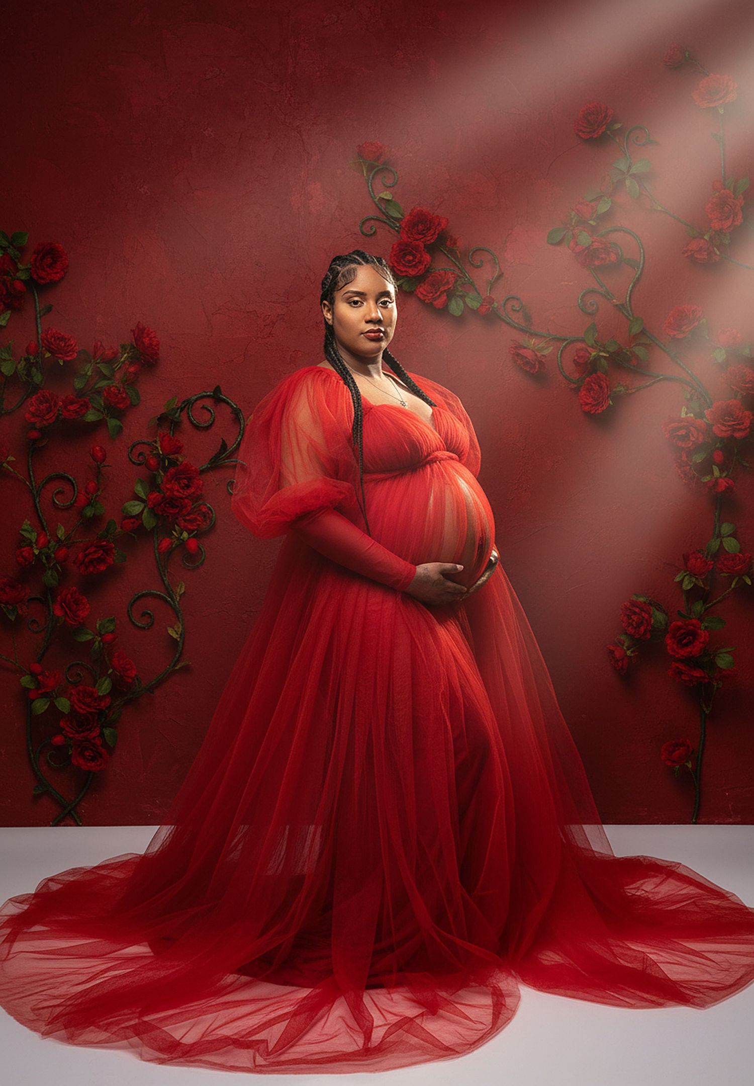 A stunning maternity photoshoot featuring a flowing red tulle gown against a moody backdrop with climbing vines.