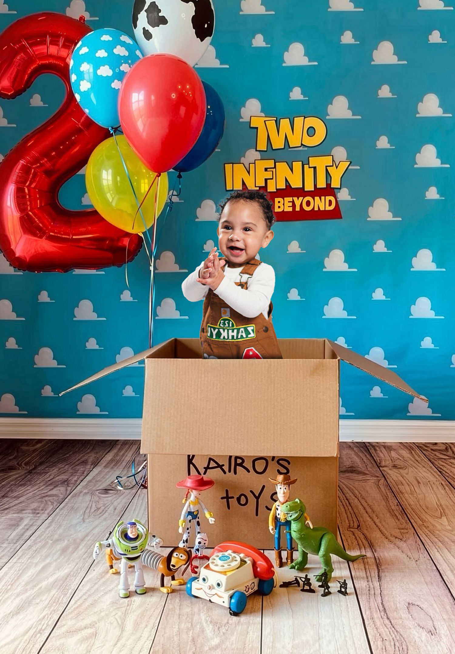 Toddler in a Toy Story themed 2nd birthday photo with balloons, Buzz Lightyear toys, and a Kairo's Toys box.