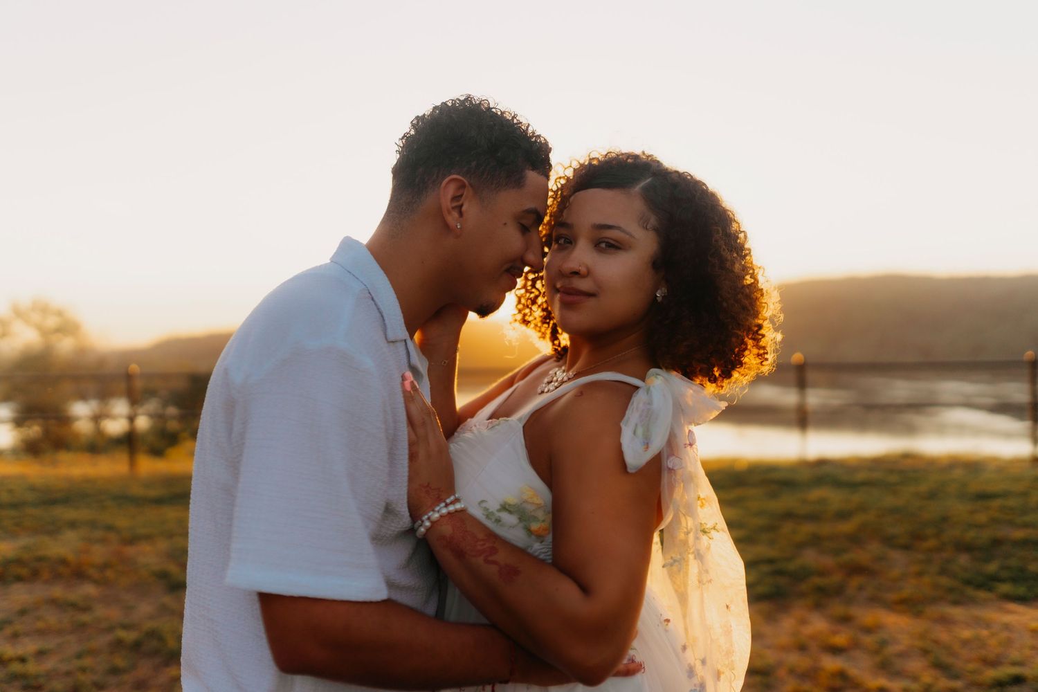 Romantic couple embraces during golden hour photoshoot in a scenic outdoor setting.