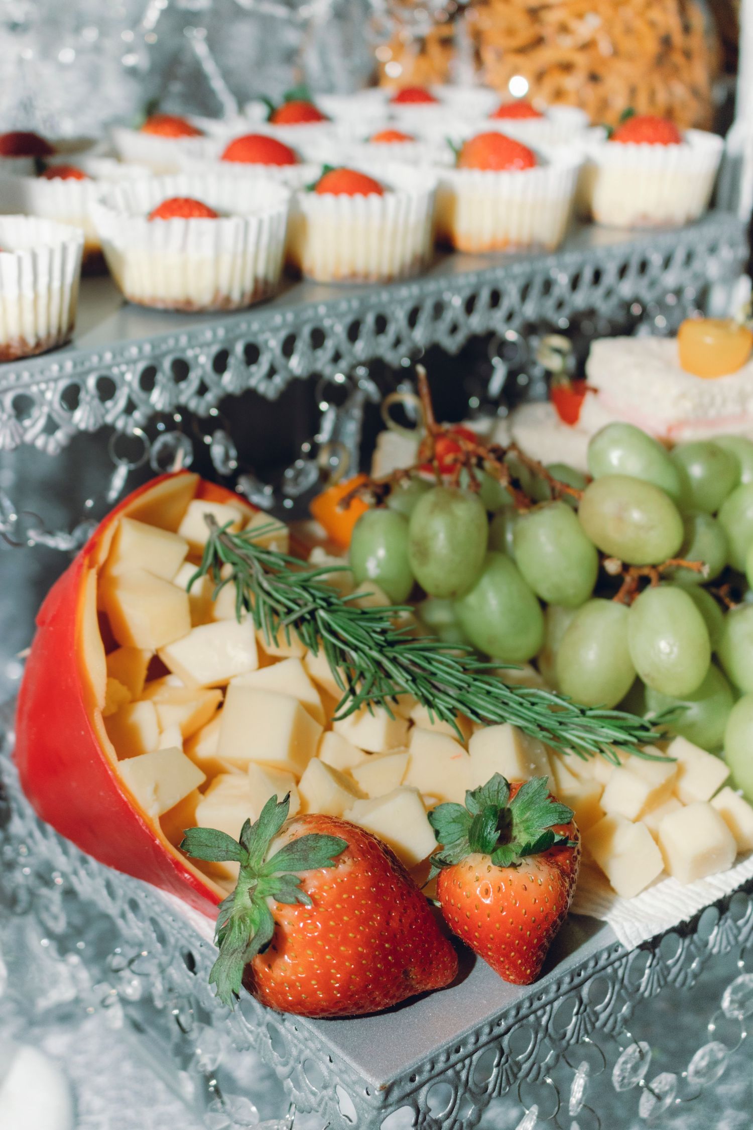 Fresh fruit and cheese platter featuring green grapes, diced cheese cubes, red strawberries and garnished with herbs.