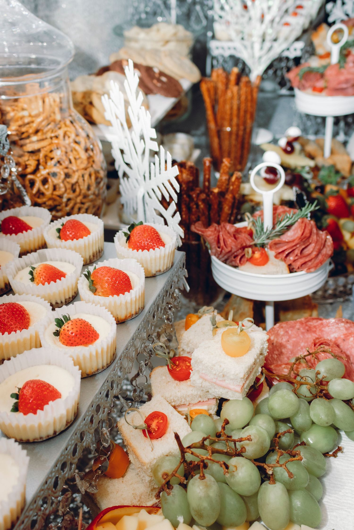 Fresh strawberries and green grapes arranged on a dessert table with cupcakes and pastries for an elegant party spread.