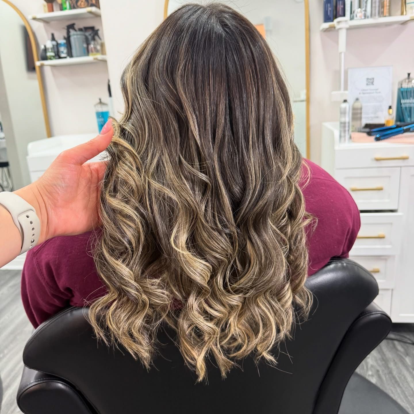 Close-up view of a blonde balayage hairstyle with soft layered waves showing transition from dark roots to light ends.
