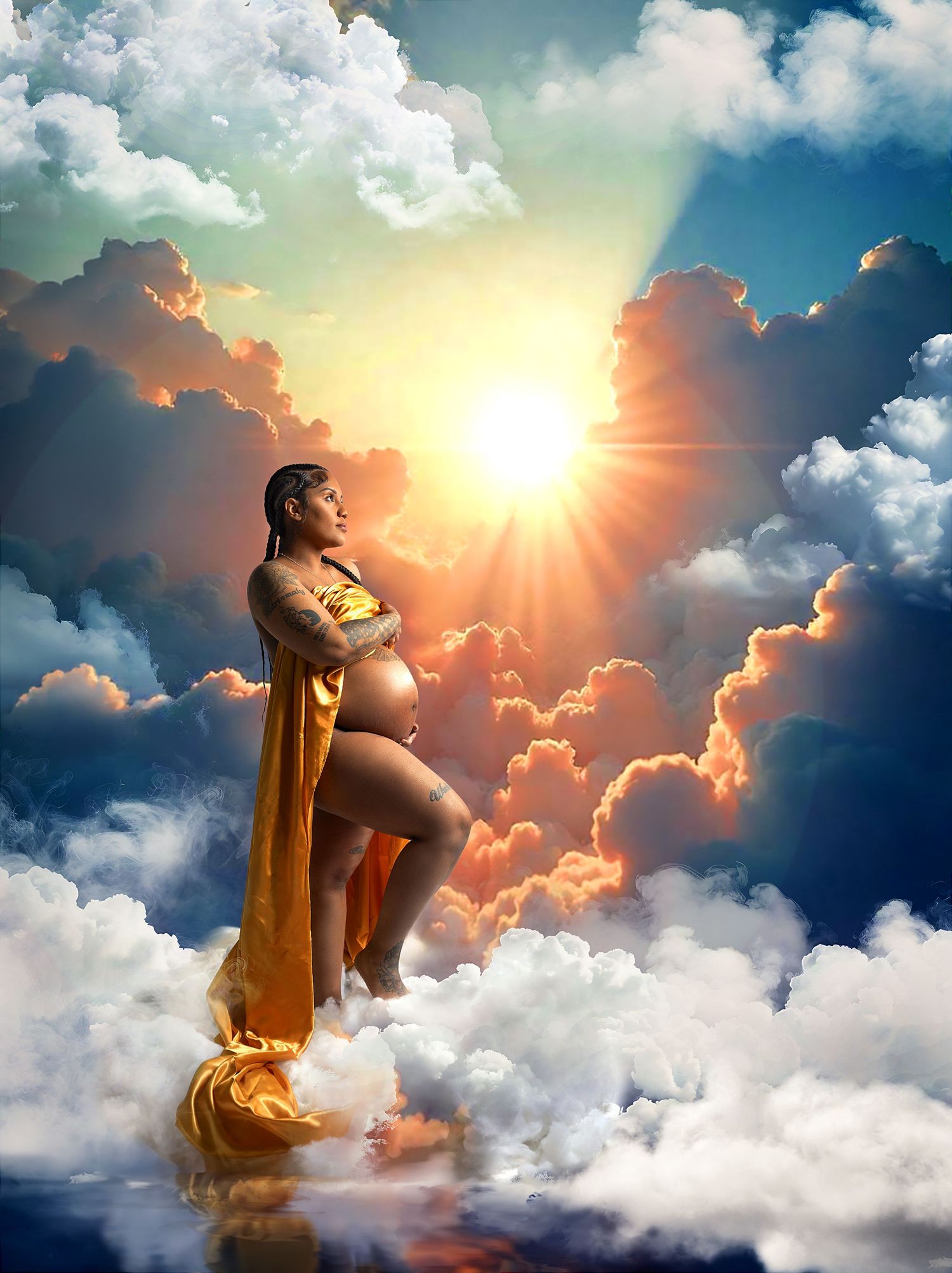 Dramatic maternity portrait against sunset sky with golden clouds and sun rays.