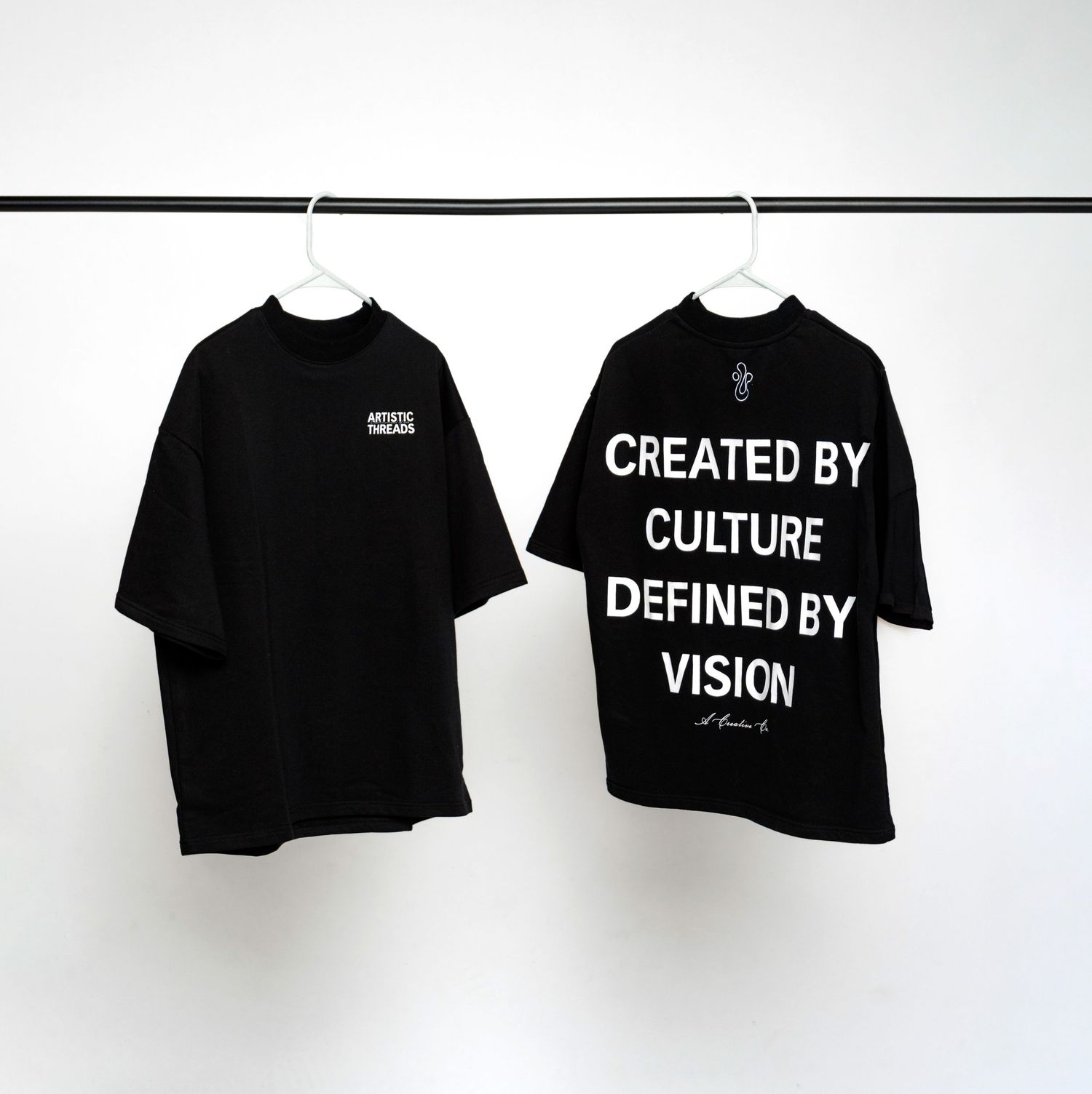 Two black t-shirts hanging on rack showing front and back designs.