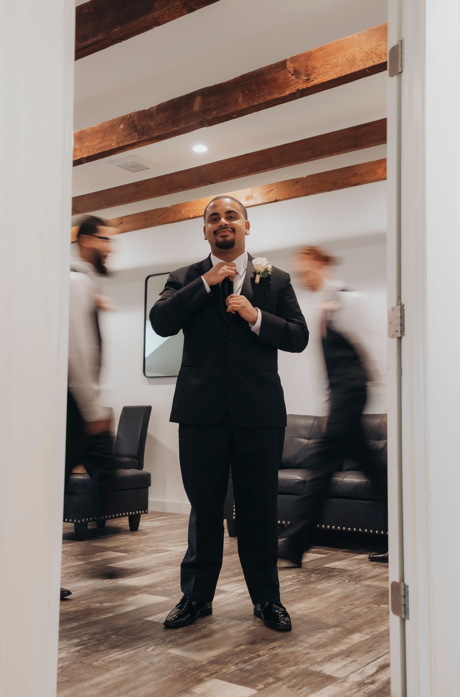 Motion blur captures a person in a black suit moving dynamically across a modern room with wooden floors and white walls.