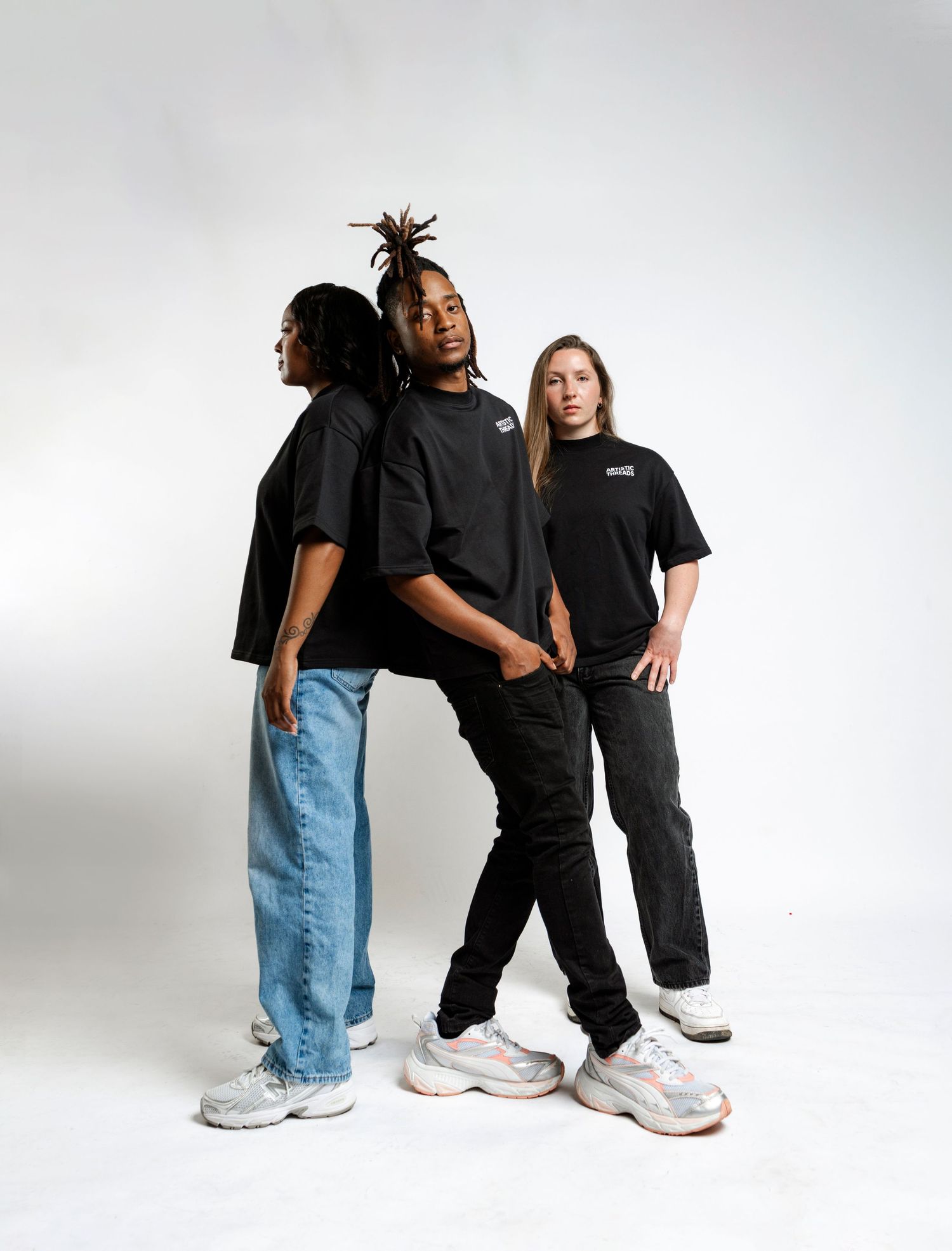 Three people in casual streetwear pose together against a white backdrop.