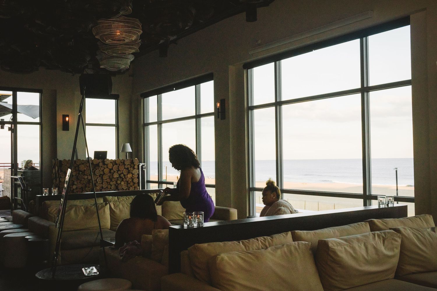 A panoramic view shows multiple small dining tables inside a cozy restaurant with large windows overlooking the city.