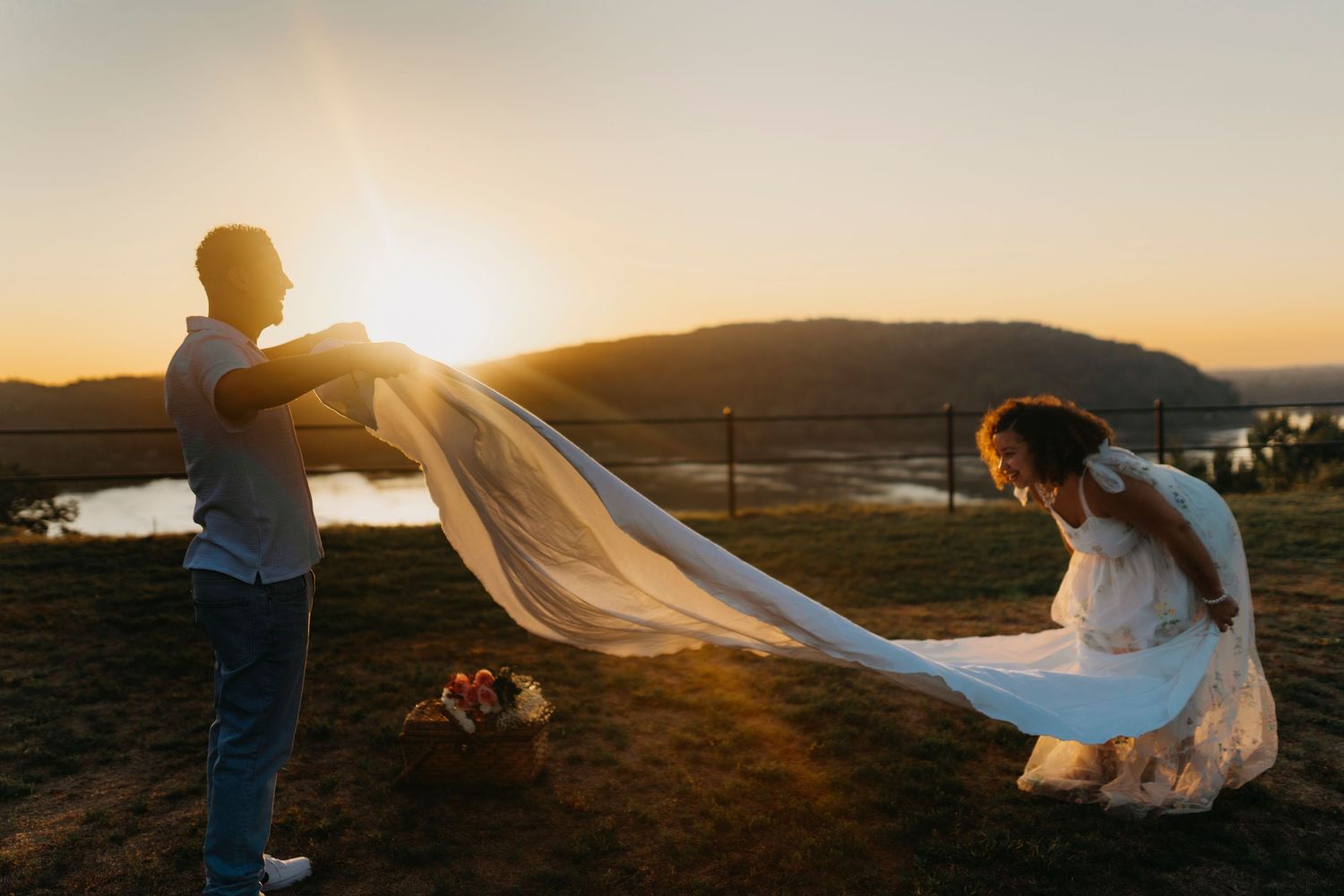 A couple poses together during a romantic sunset photoshoot in a scenic mountain landscape.