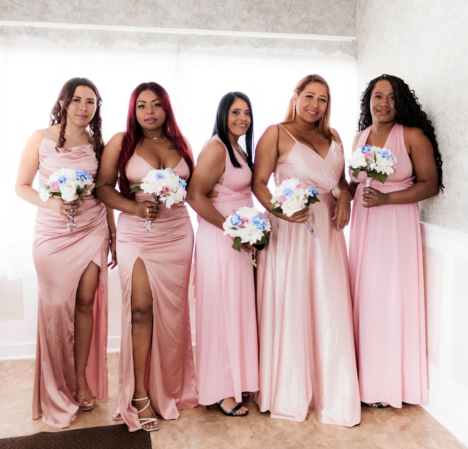 Bridesmaids in matching pink dresses hold white bouquets.