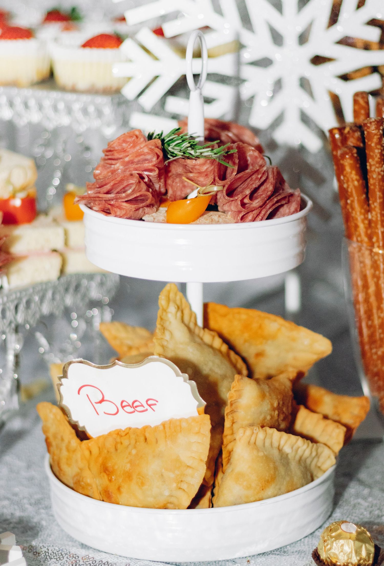 White ceramic tiered serving platter with golden fried dumplings and dip arranged for holiday entertaining with snowflake decor.