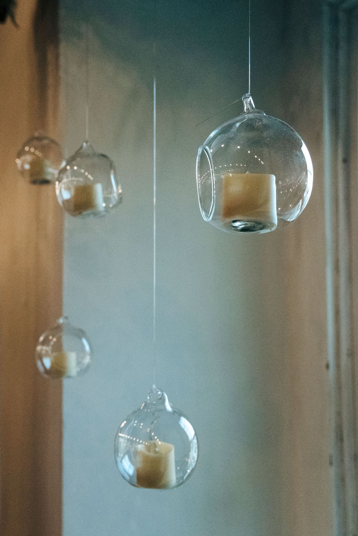Hanging glass globe candle holders suspended by thin strings for elegant wedding decor.