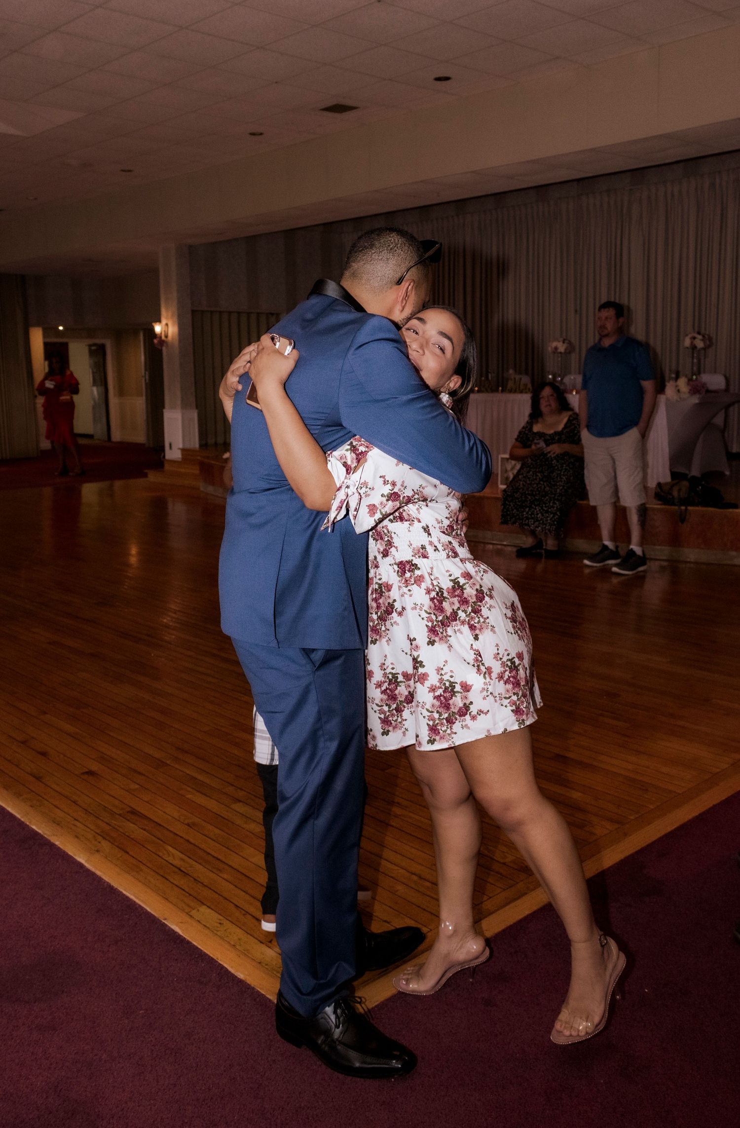 Couple sharing an intimate dance moment on wooden floor at wedding reception.
