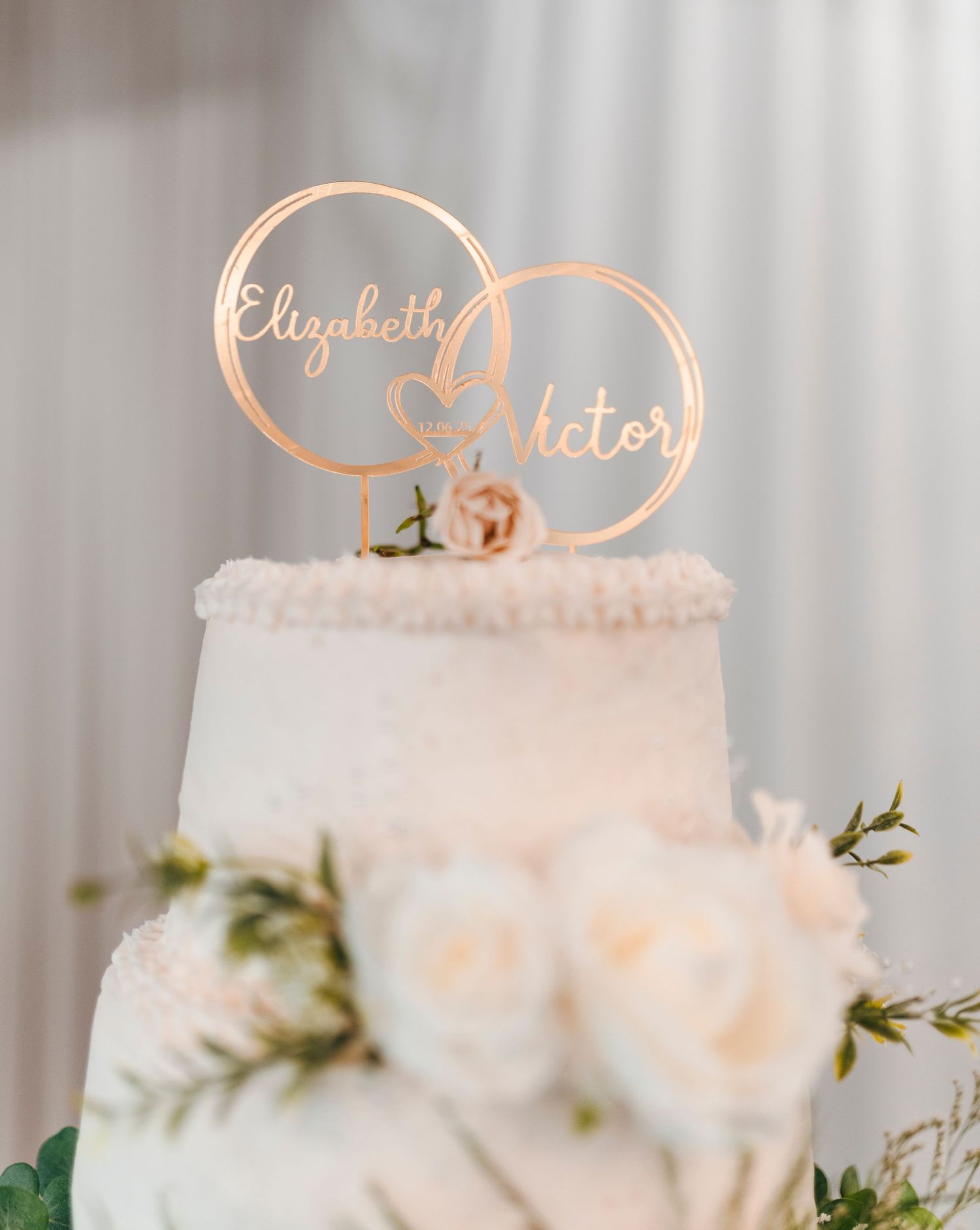 Three elegant white wedding cakes with gold accents and floral decorations displayed on a light gray background.