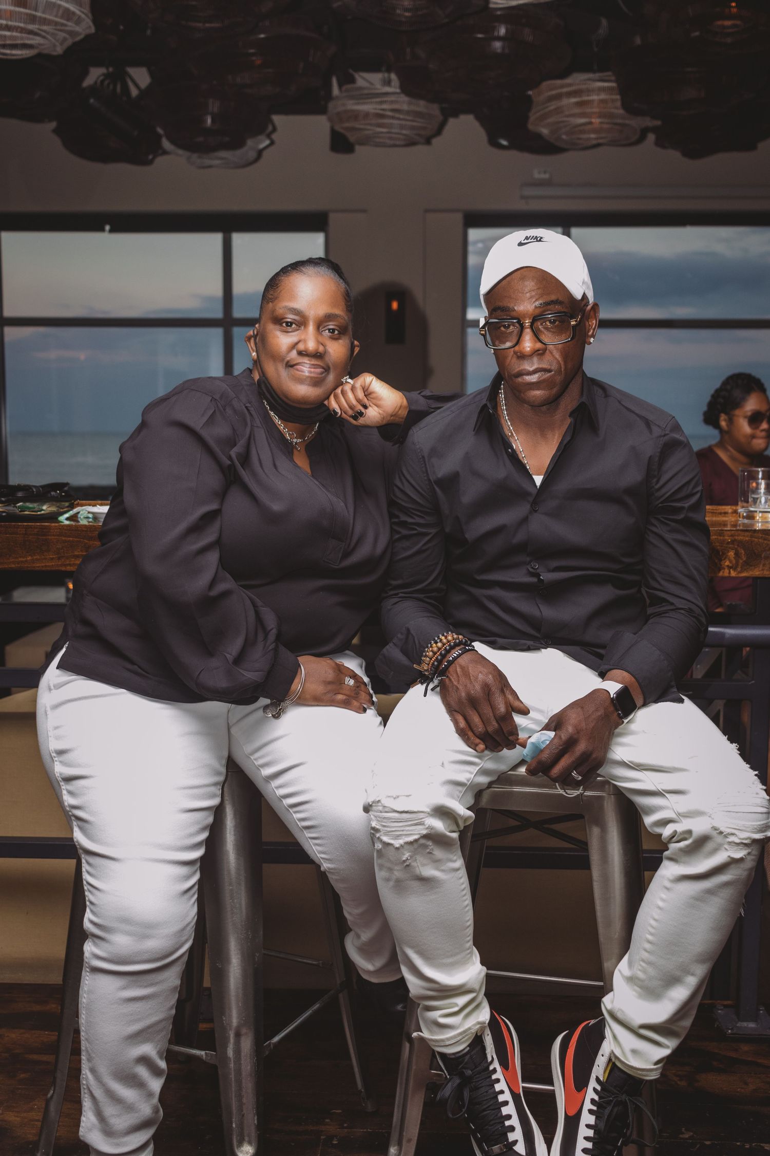 Two people sitting casually at a restaurant bar wearing contrasting black and white outfits together.