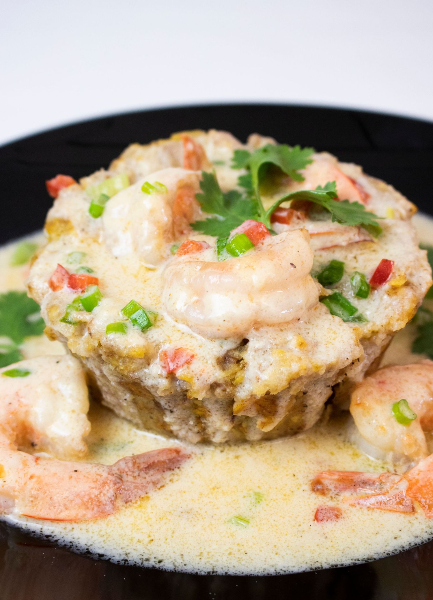 Stuffed artichoke with shrimp in creamy sauce garnished with herbs and red pepper flakes.