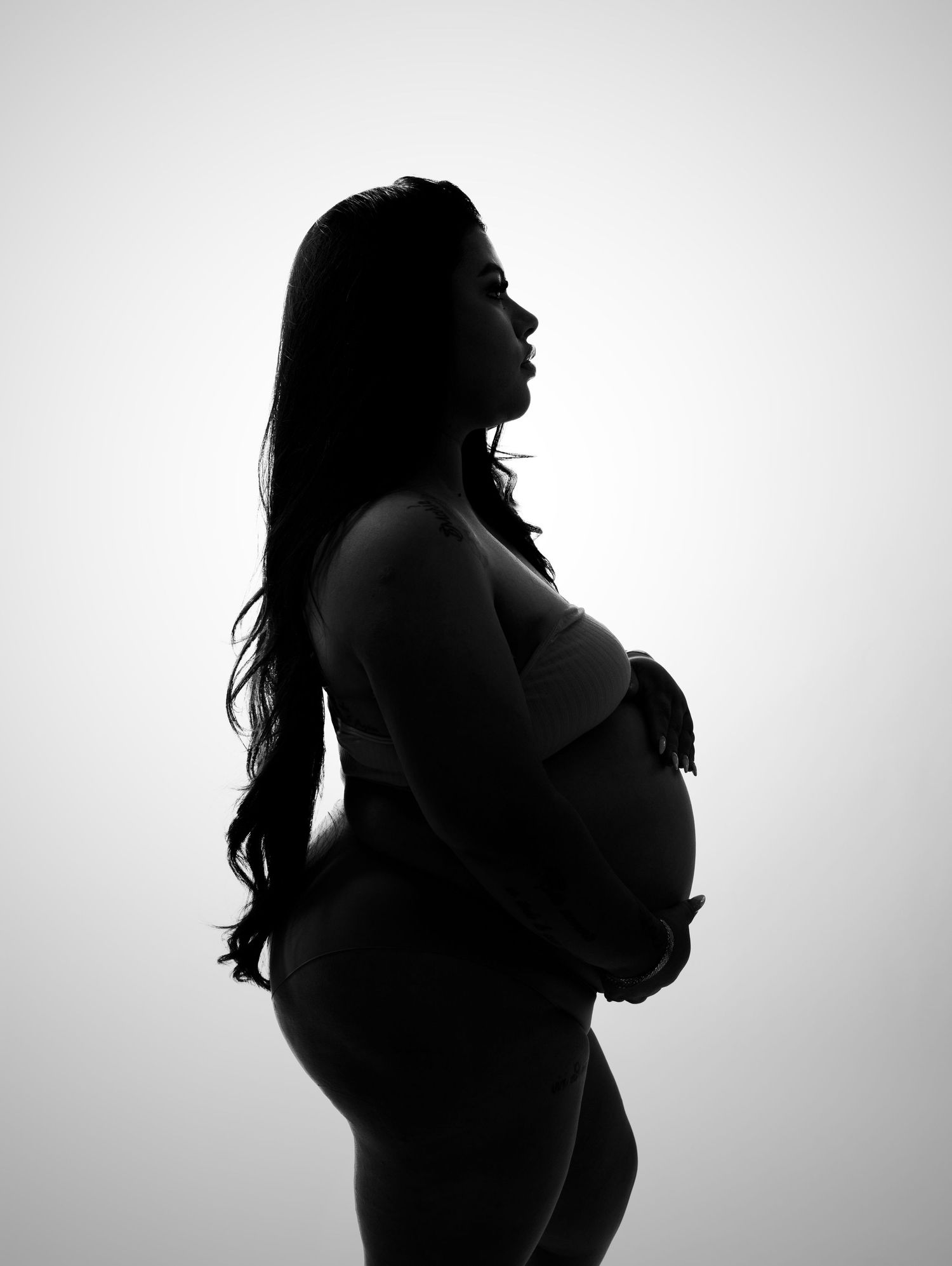 Artistic silhouette of pregnant woman's profile against white background.