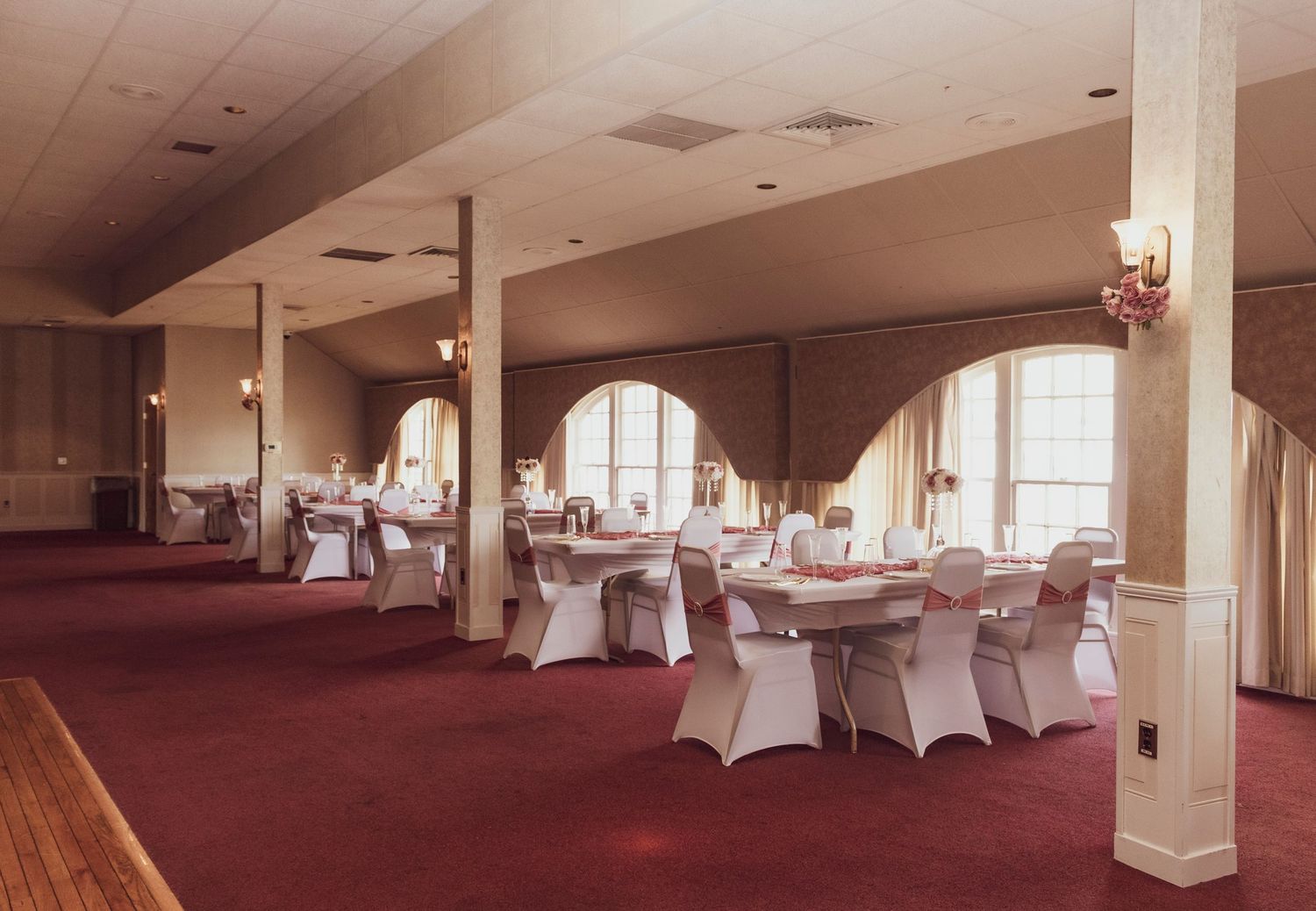 Elegant reception hall with white-covered tables and chairs set up for a formal event.