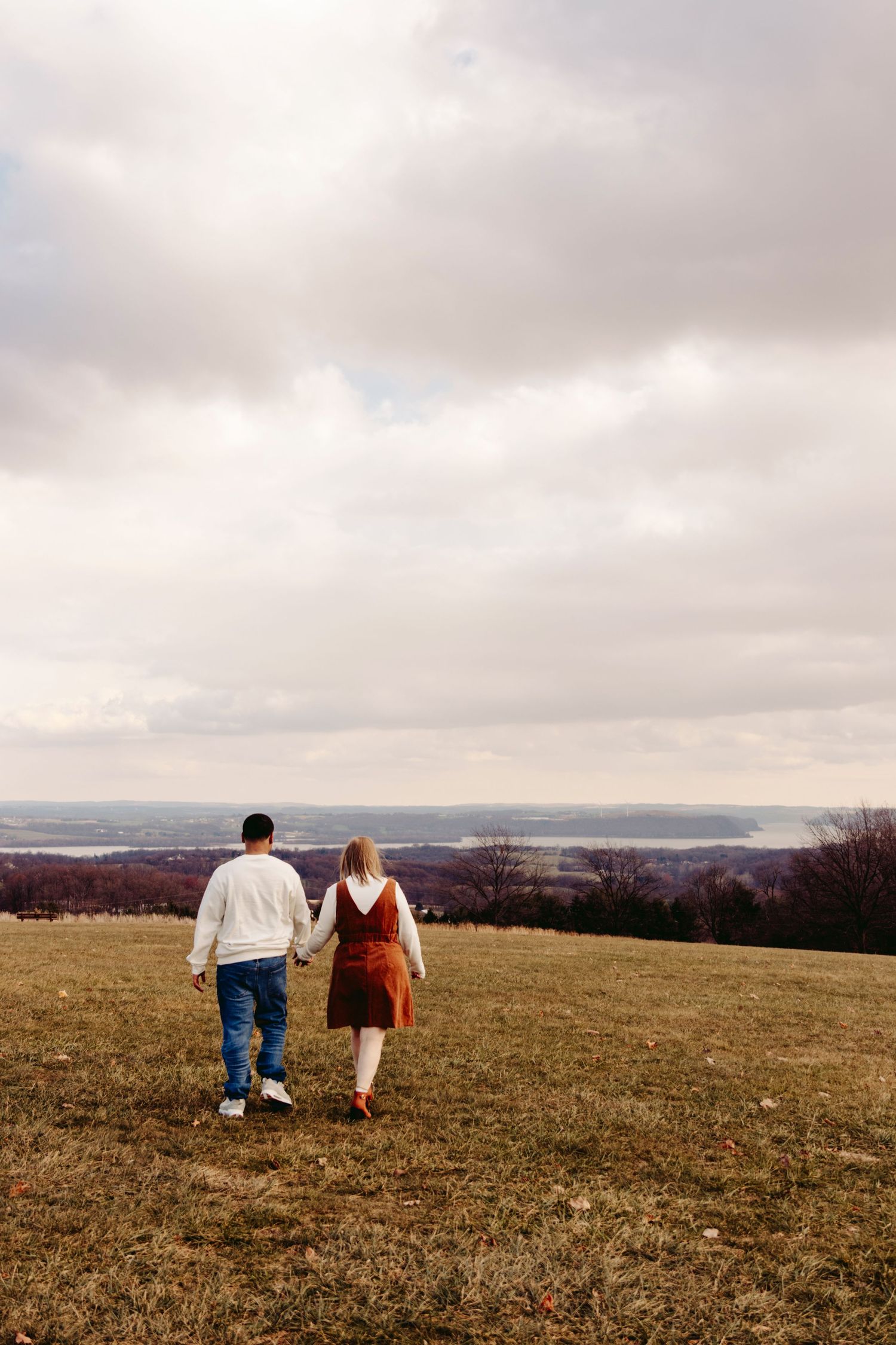 Couple walking together on a hilltop overlooking an autumn landscape with their dog in a progressive series of photos.