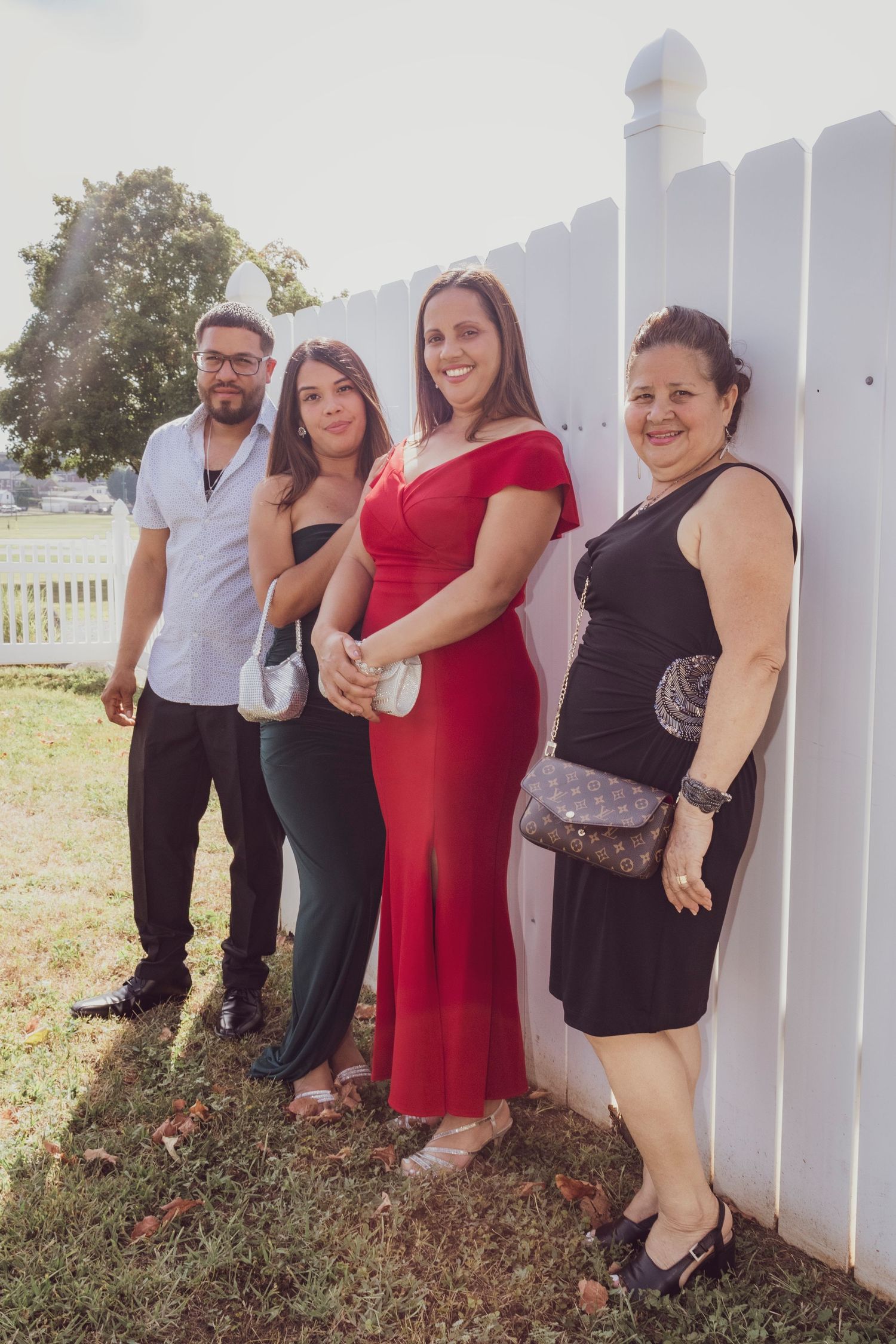 Group poses against white picket fence at outdoor event.