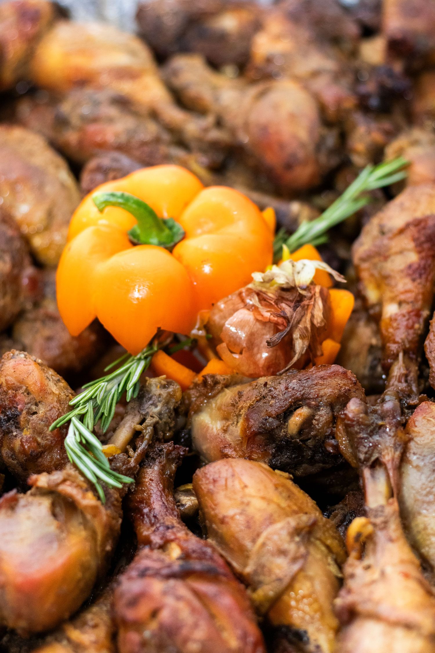 Grilled chicken garnished with bright orange cherry tomatoes and fresh rosemary on a dark background.