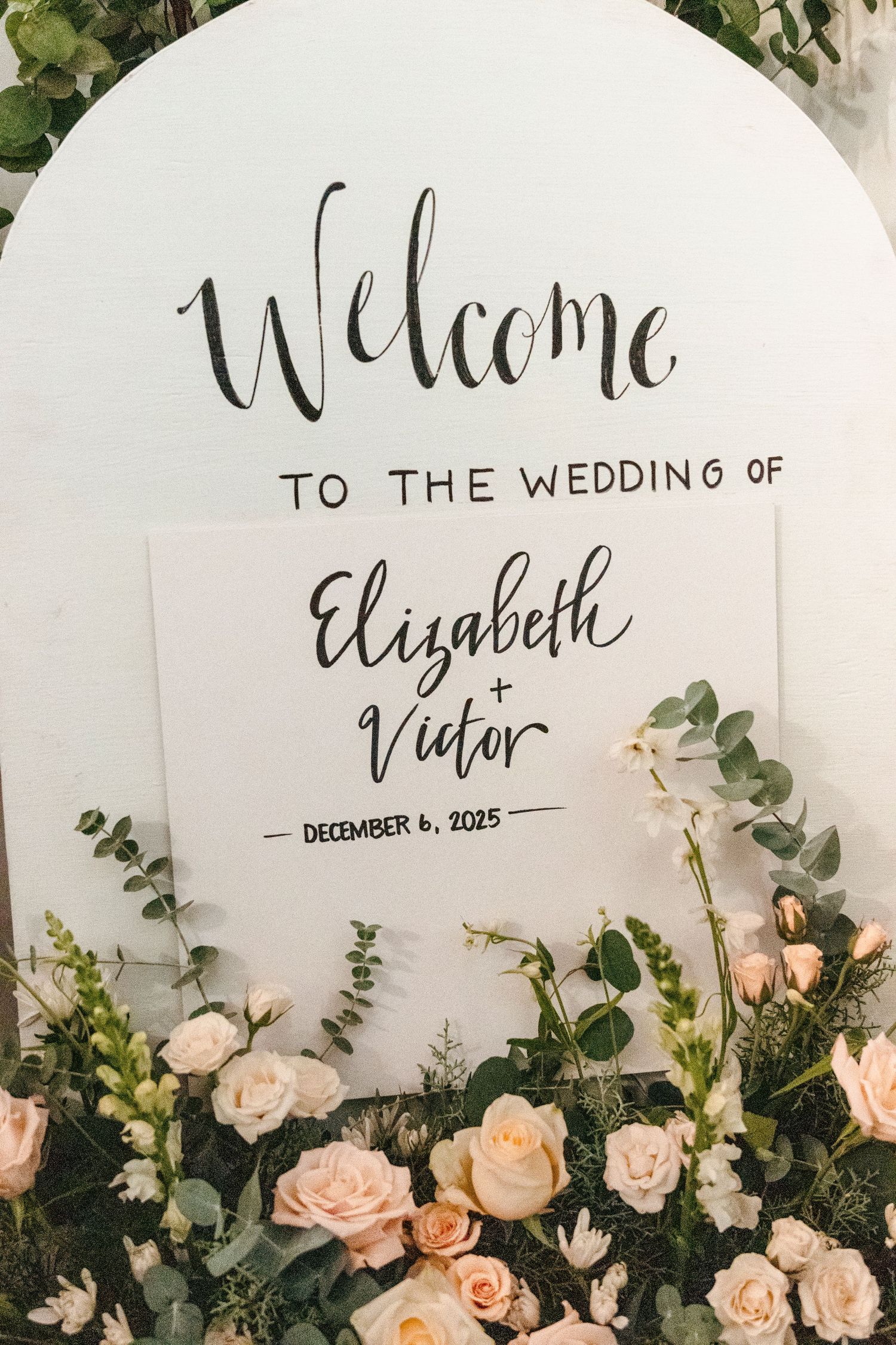 Elegant wedding welcome sign for Elizabeth and Victor, December 6 2025, adorned with blush roses and greenery.