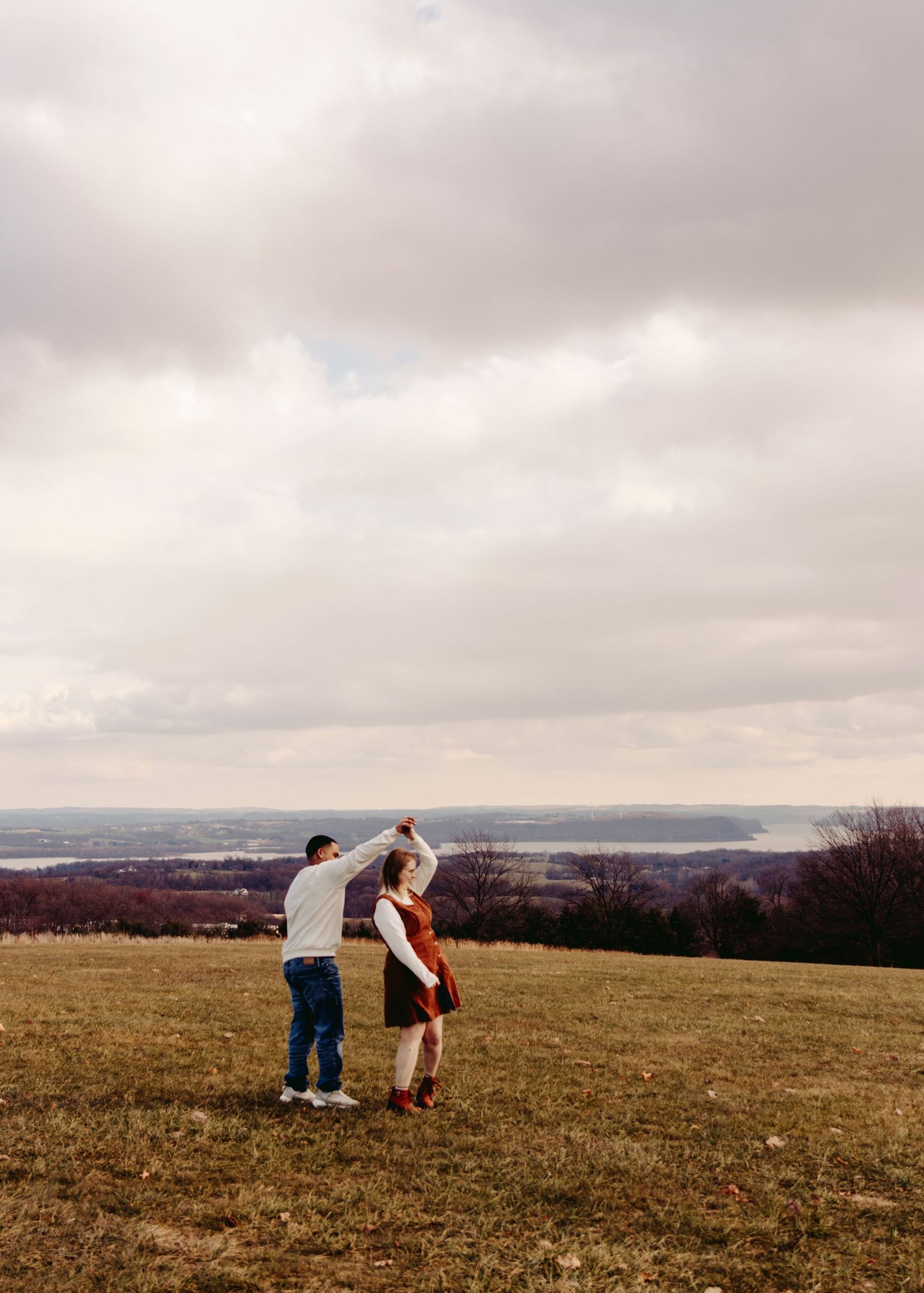 Four sequential images show two people collecting samples in a grassy hilltop field with cloudy sky in the background.