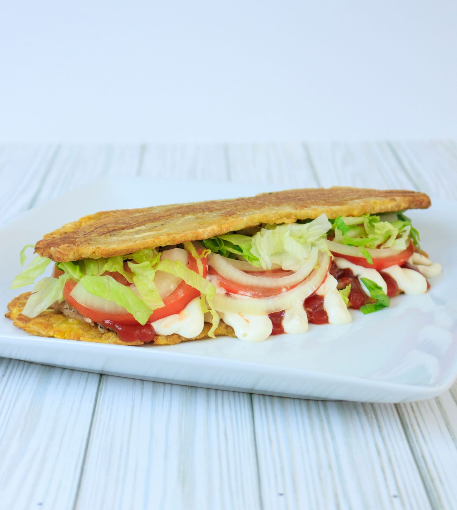 Fresh submarine sandwich filled with lettuce, tomatoes, and onions on white plate.