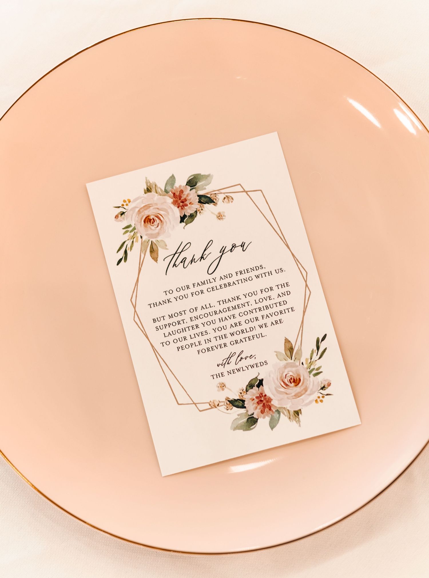 Elegant floral wedding thank you card with blush roses on a pink plate with gold rim.