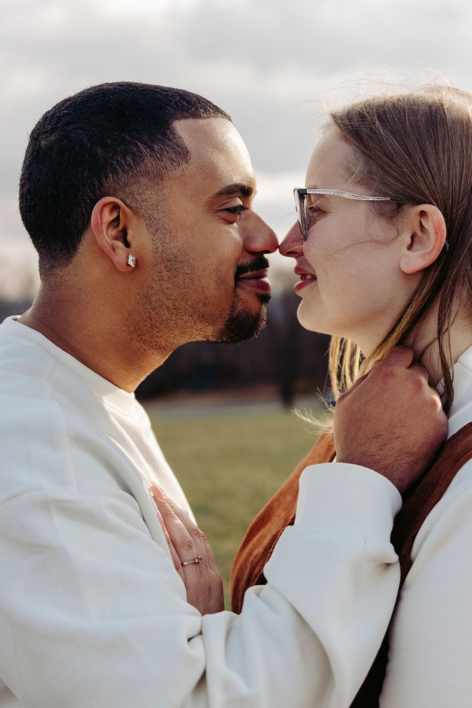 A romantic couple in white outfits sharing tender moments together against a scenic outdoor background.