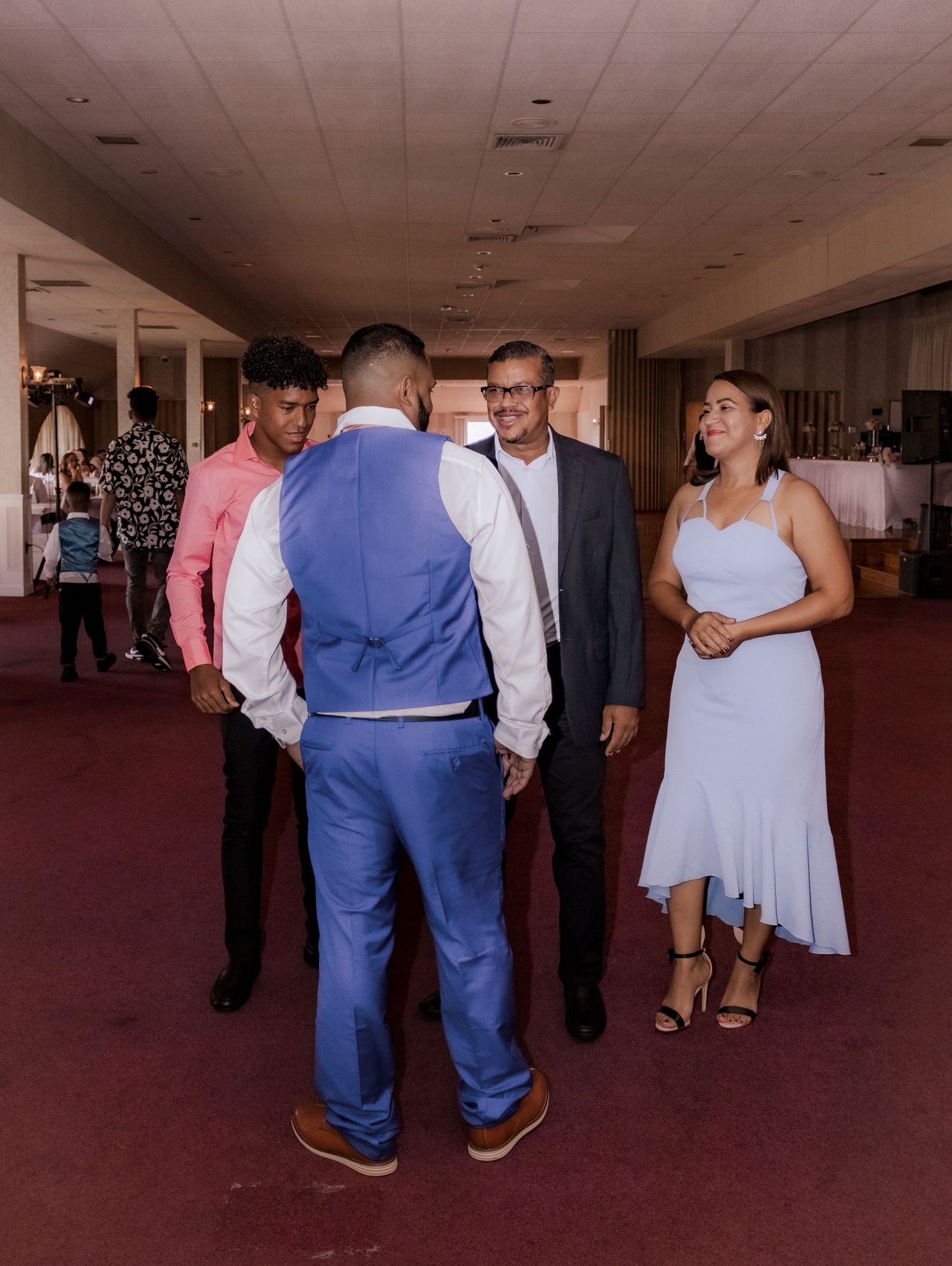 Wedding party members in formal attire gathered in venue hallway.