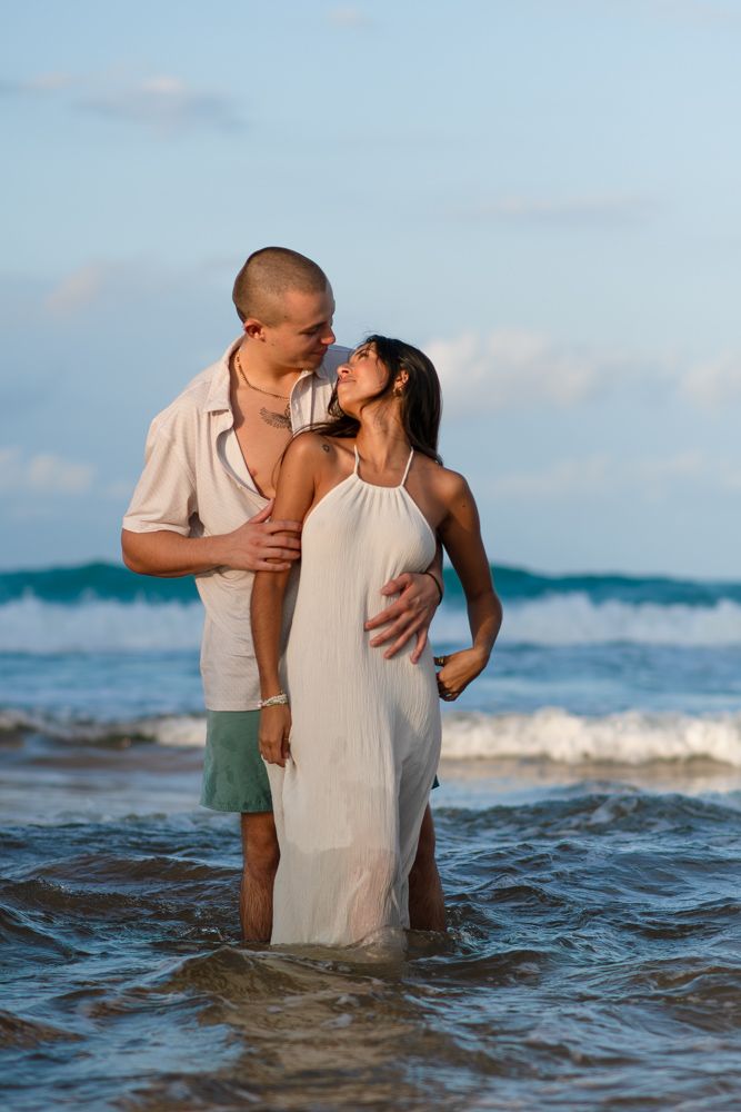 Engagement couple standing in ocean waves on La Pared beach Luquillo Puerto Rico