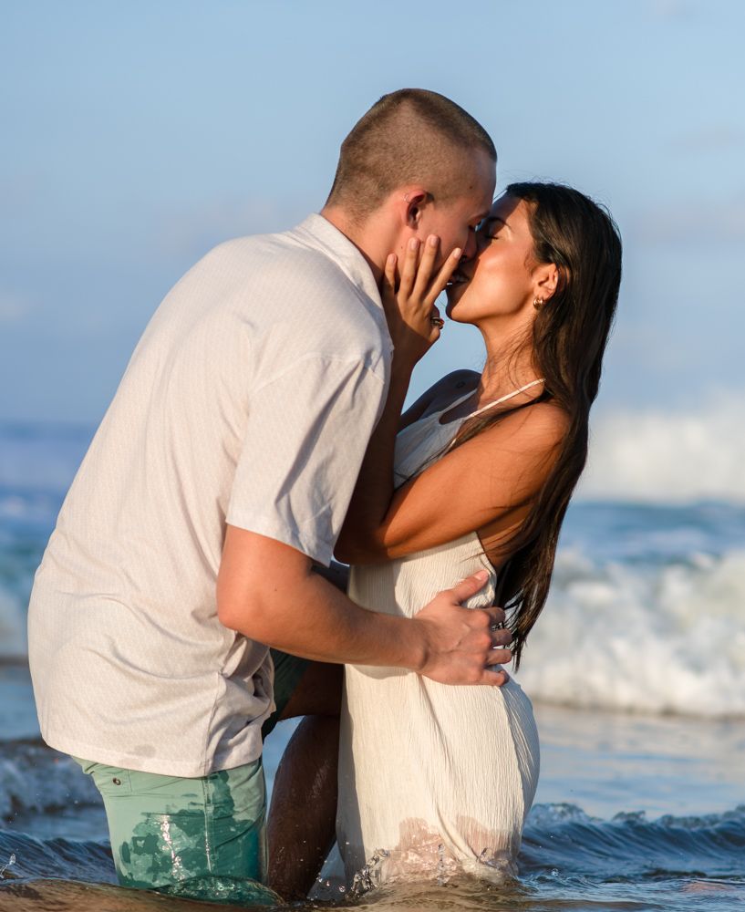 Engaged couple embracing on La Pared beach with ocean waves in Luquillo Puerto Rico