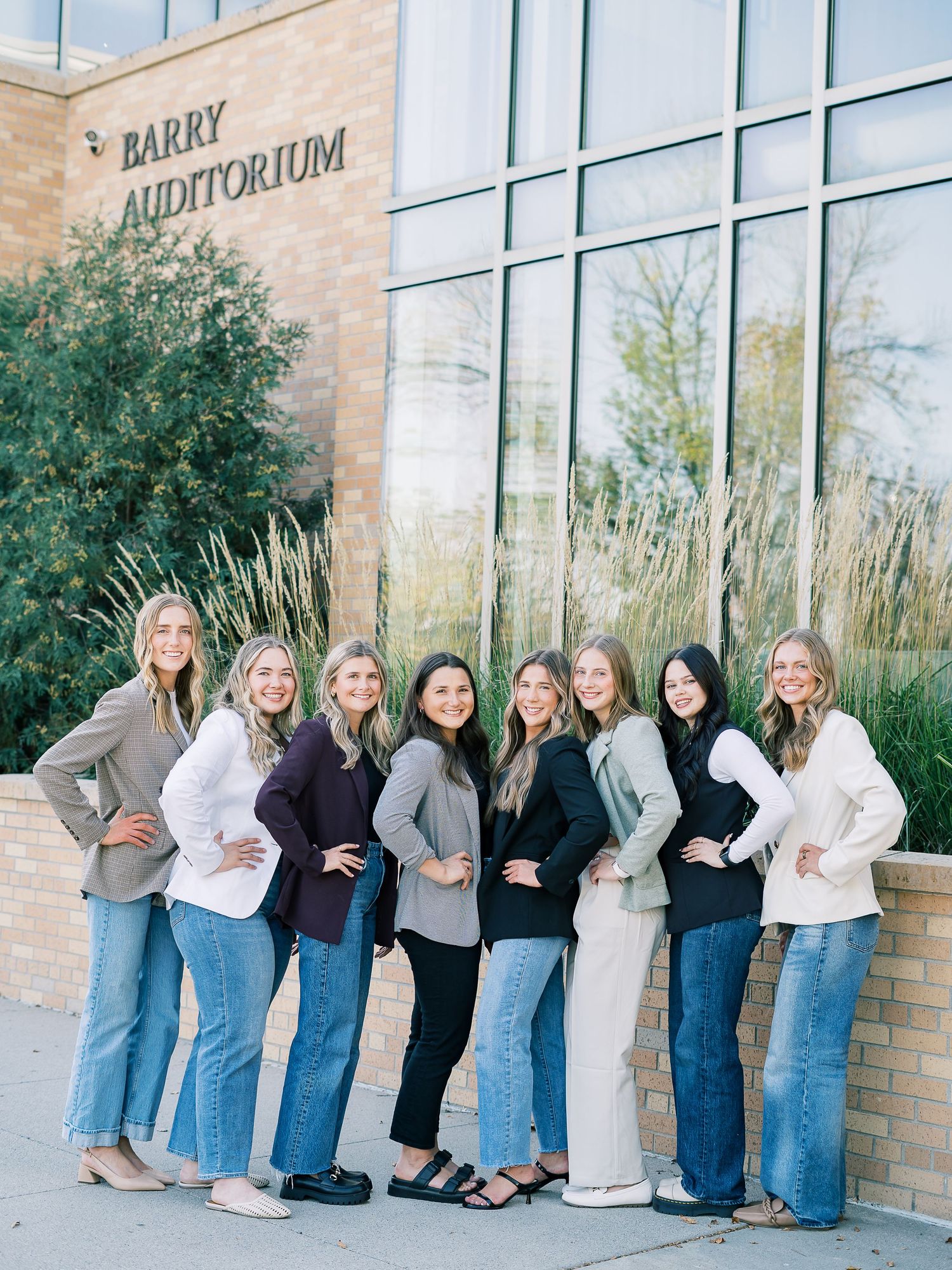 A group wearing matching jeans and neutral tops poses together against a brick wall in three candid shots.