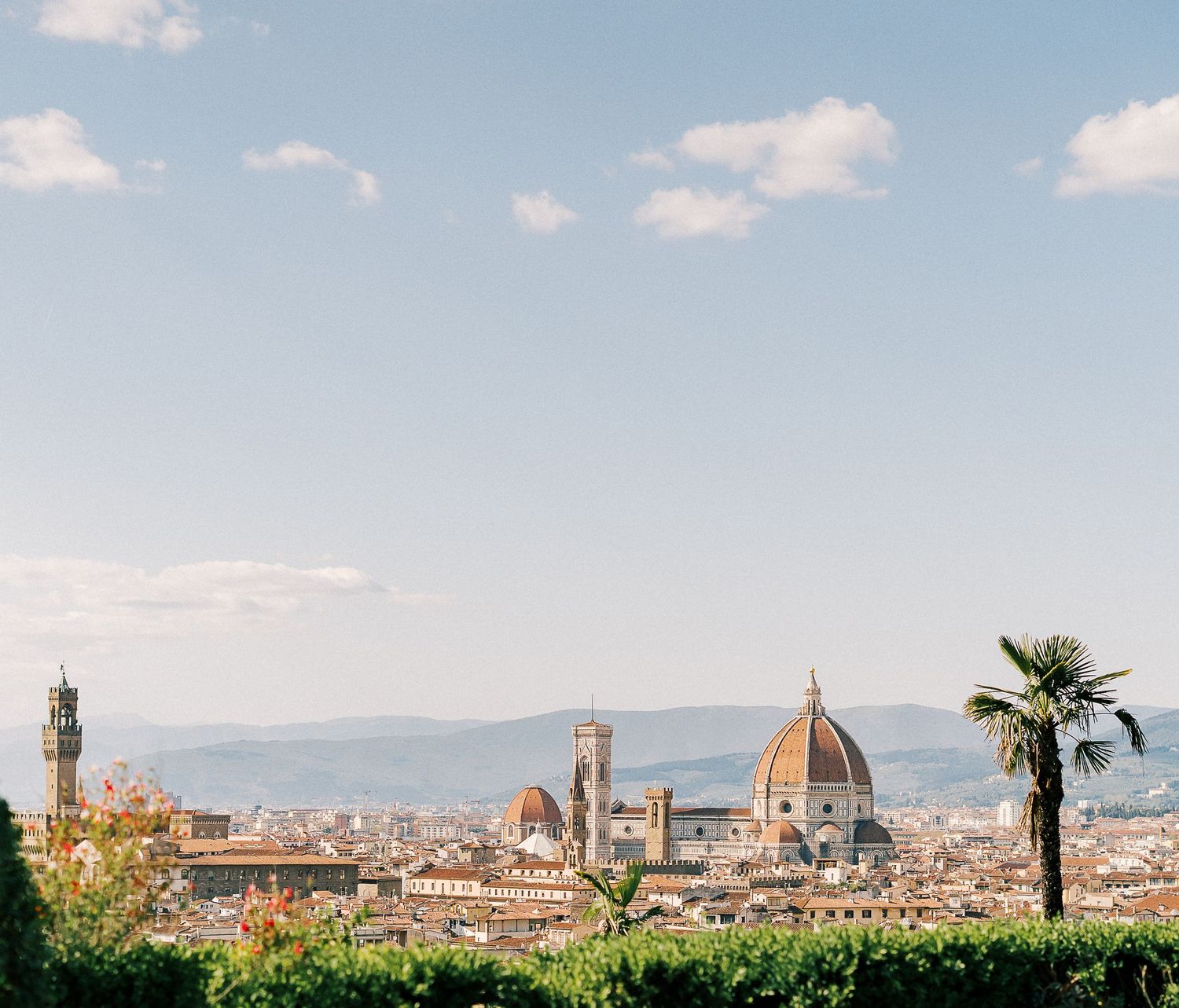 Panoramic cityscape view of Florence, Italy with historic architecture and the iconic Duomo cathedral dome against blue sky.
