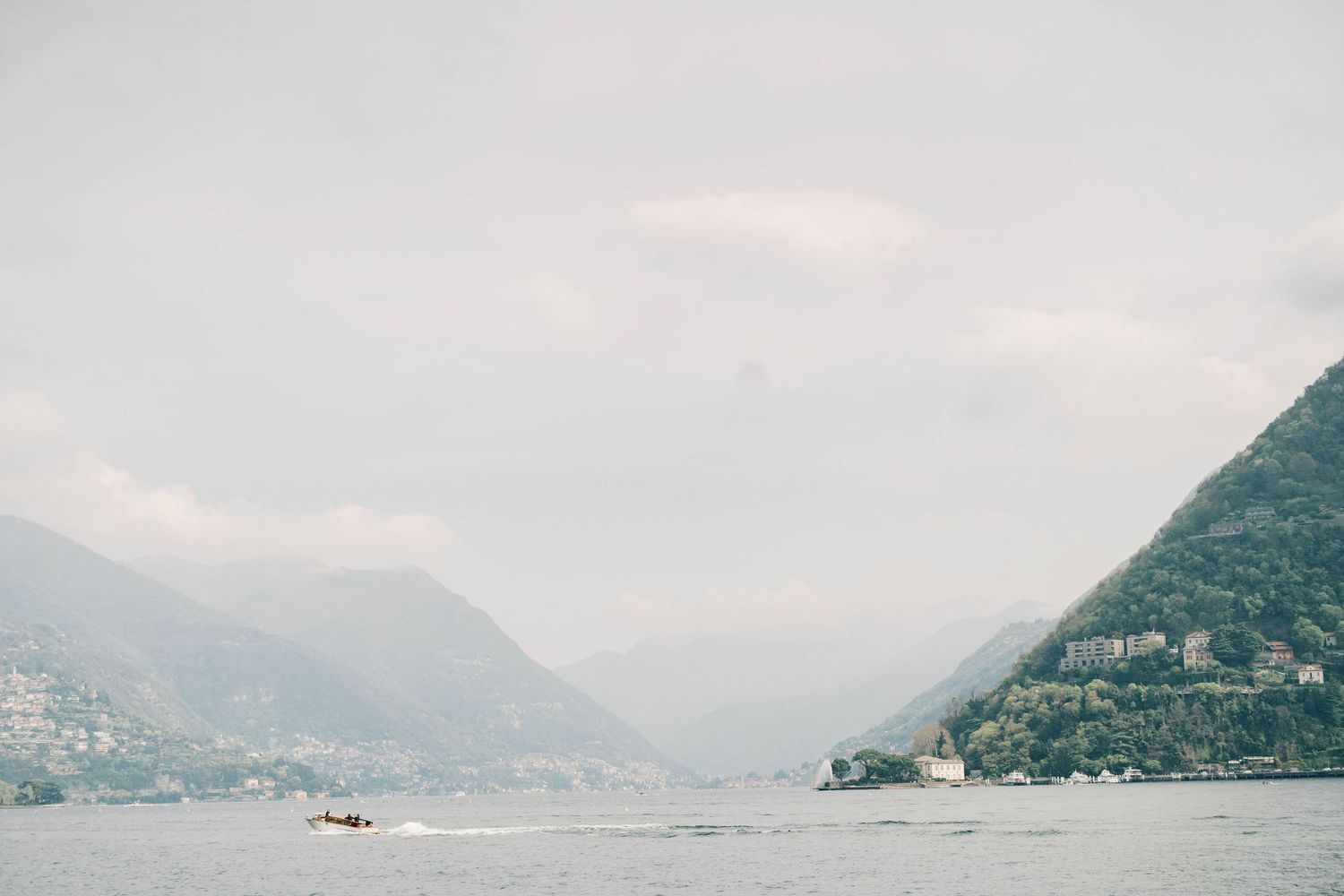 Panoramic view of a mountain lake with foggy peaks in the distance.