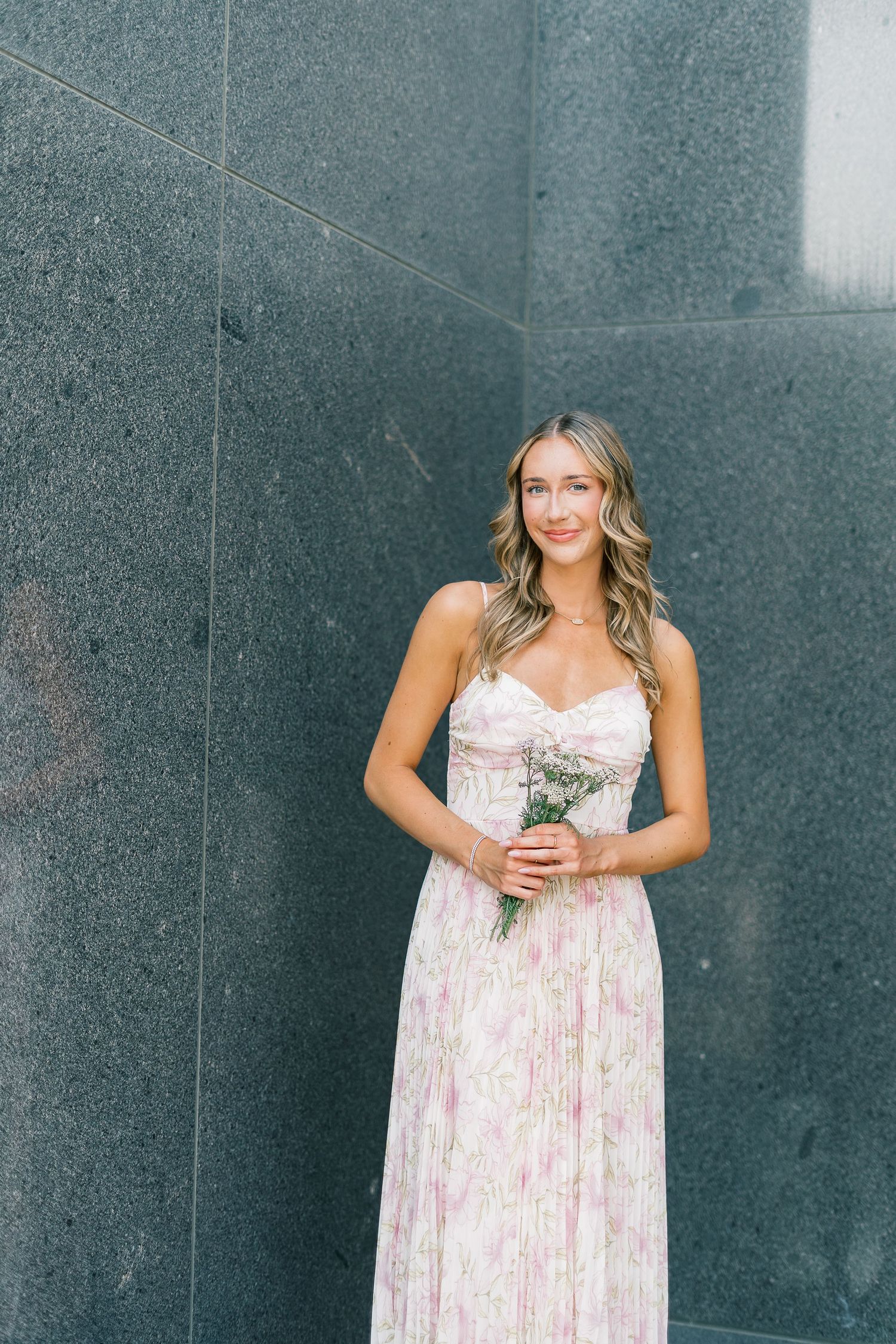 A series of outdoor portraits against a dark wall showing someone in a floral summer dress.