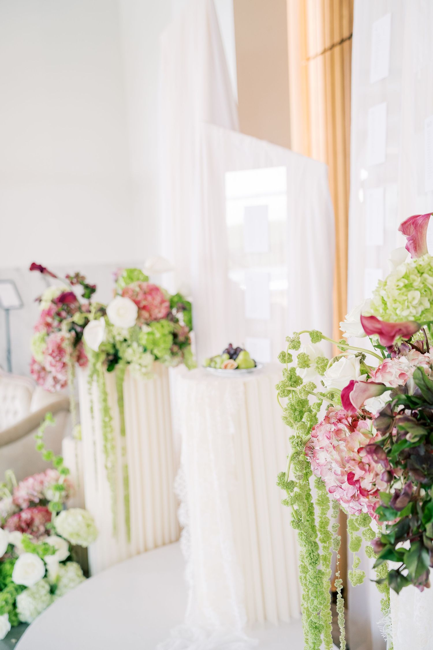 Elegant wedding ceremony aisle decorated with pink and white floral arrangements and delicate hanging greenery.