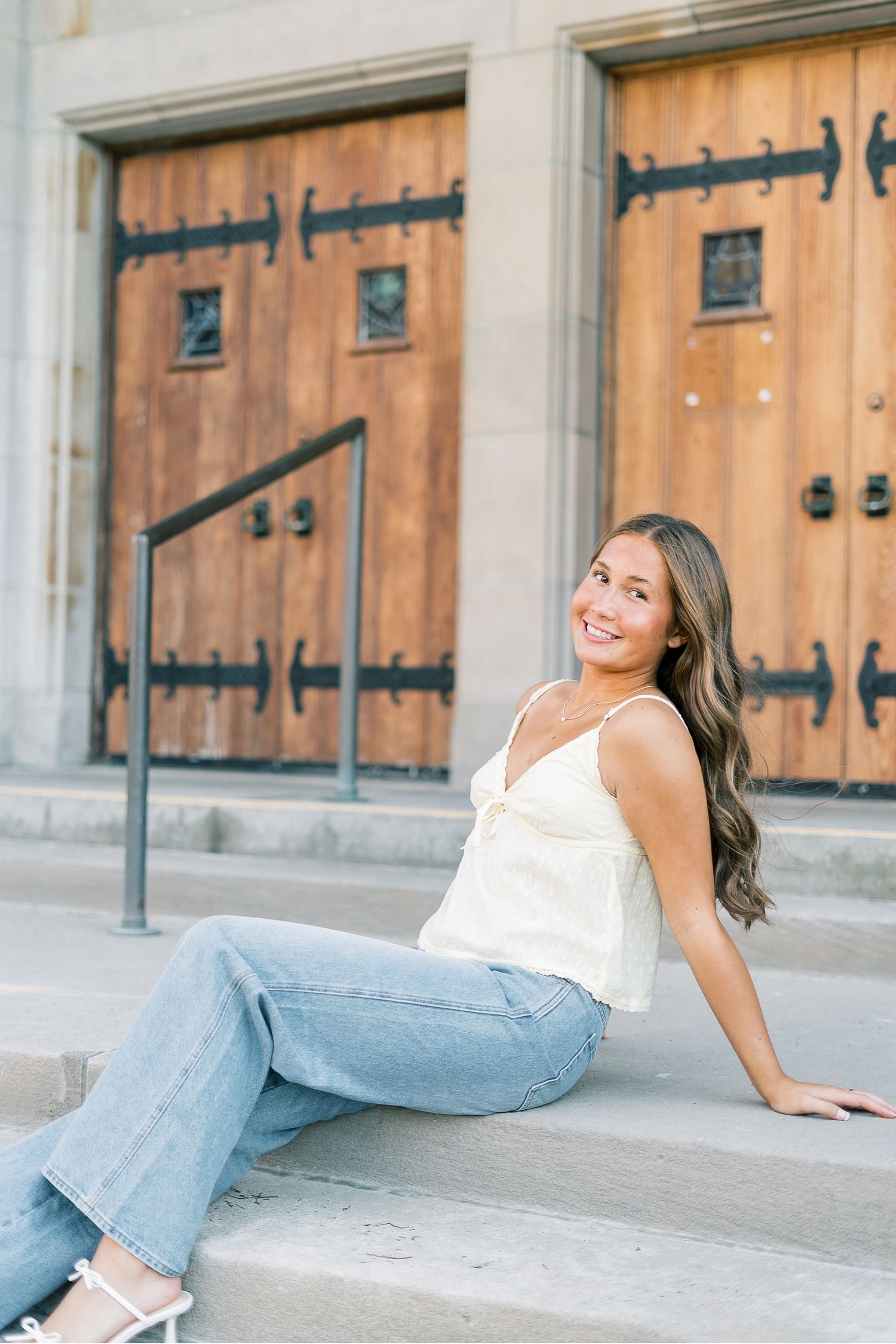 Casual portraits against a rustic wooden barn door showing someone in jeans and a white top.
