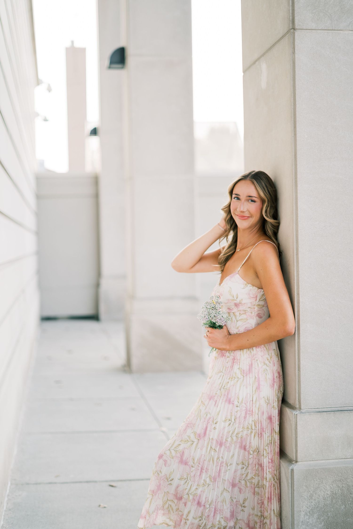 A floral sundress is showcased against white architectural columns in an elegant outdoor setting.